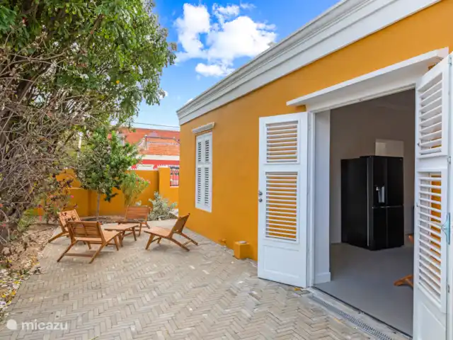 Resort privé Curaçao pour les groupes | Curaçao, Curaçao-Centre, Willemstad - villa Charmante terrasse latérale avec de jolis sièges sous les arbres tropicaux, idéale pour des moments de détente sous le vent de la ville