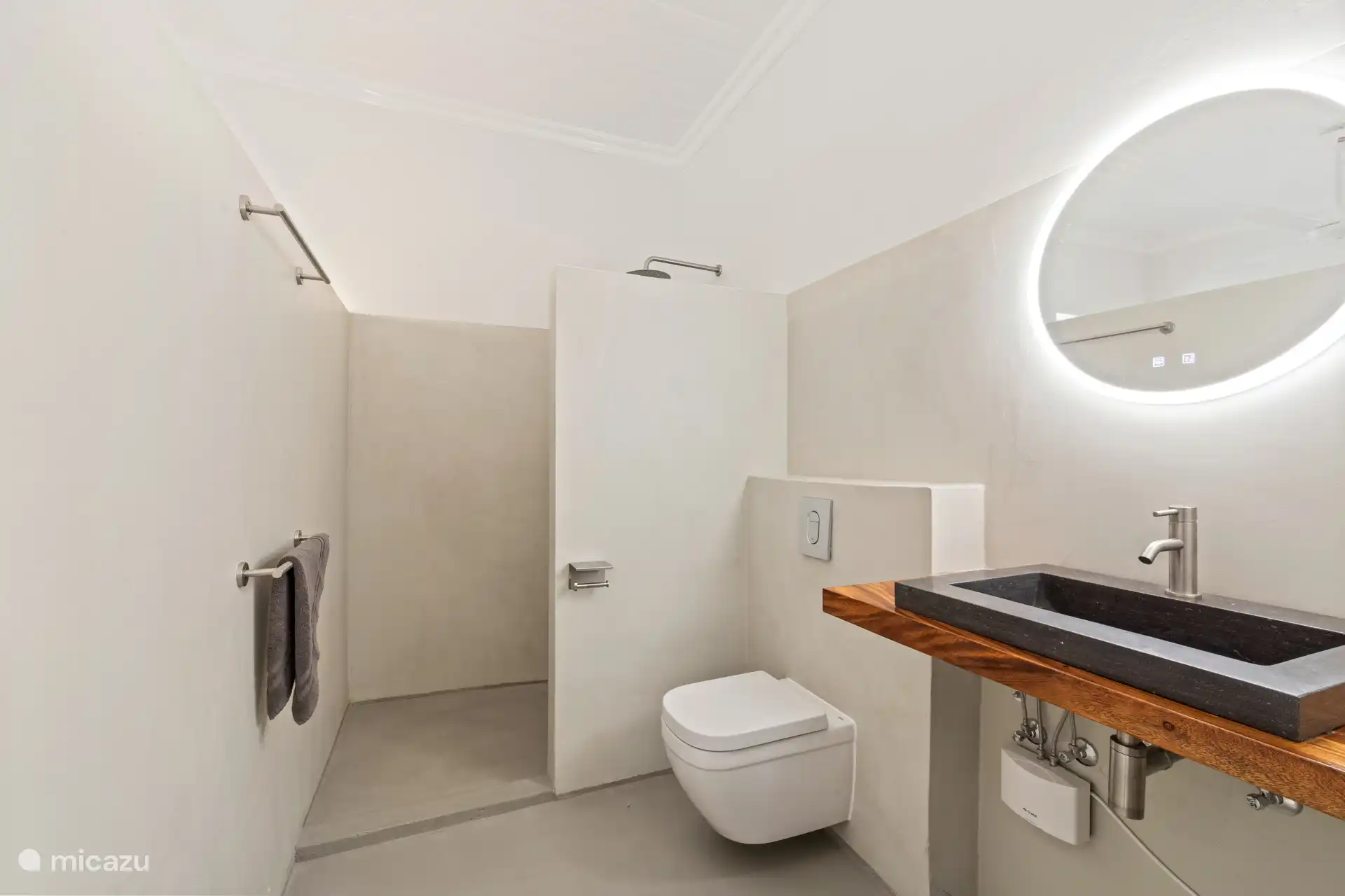 Spacious bathroom with rain shower, natural stone sink and warm wooden accent