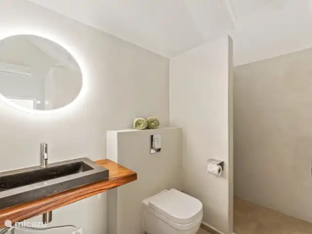Resort privé Curaçao pour les groupes | Curaçao, Curaçao-Centre, Willemstad - villa Salle de bain lumineuse avec douche à effet pluie, lavabo en pierre naturelle et toilettes suspendues modernes. Fini avec des matériaux chaleureux et un éclairage indirect pour une atmosphère apaisante