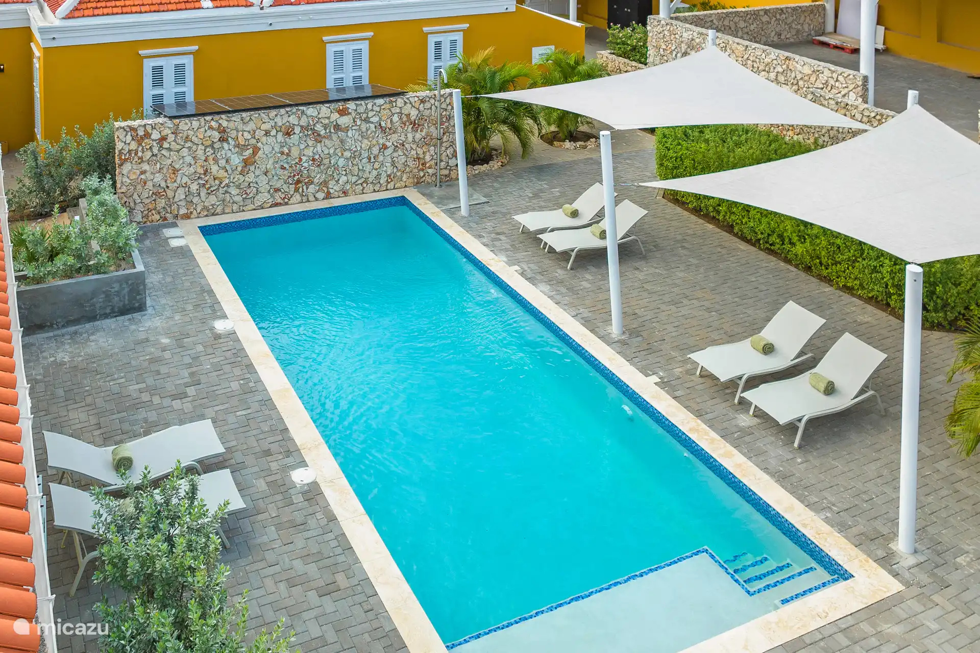 10×4 m saltwater pool with shallow end for relaxing in the water. Surrounded by tropical greenery and Fermob sun loungers – an oasis of calm on Curaçao