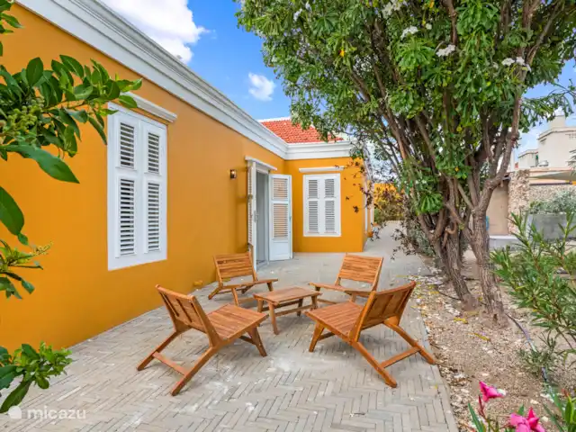 Resort privé Curaçao pour les groupes | Curaçao, Curaçao-Centre, Willemstad - villa Charmante terrasse latérale avec de jolis sièges sous les arbres tropicaux, idéale pour des moments de détente sous le vent de la ville