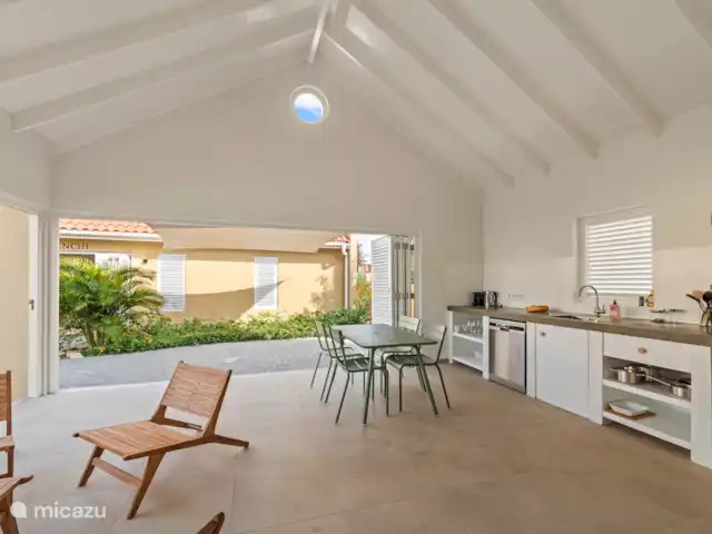 Resort privé Curaçao pour les groupes | Curaçao, Curaçao-Centre, Willemstad - villa Salon lumineux avec haut plafond, cuisine ouverte et portes à volets donnant sur la terrasse. Profitez de l’extérieur à la table à manger ou dans les chaises longues, avec vue sur le jardin tropical