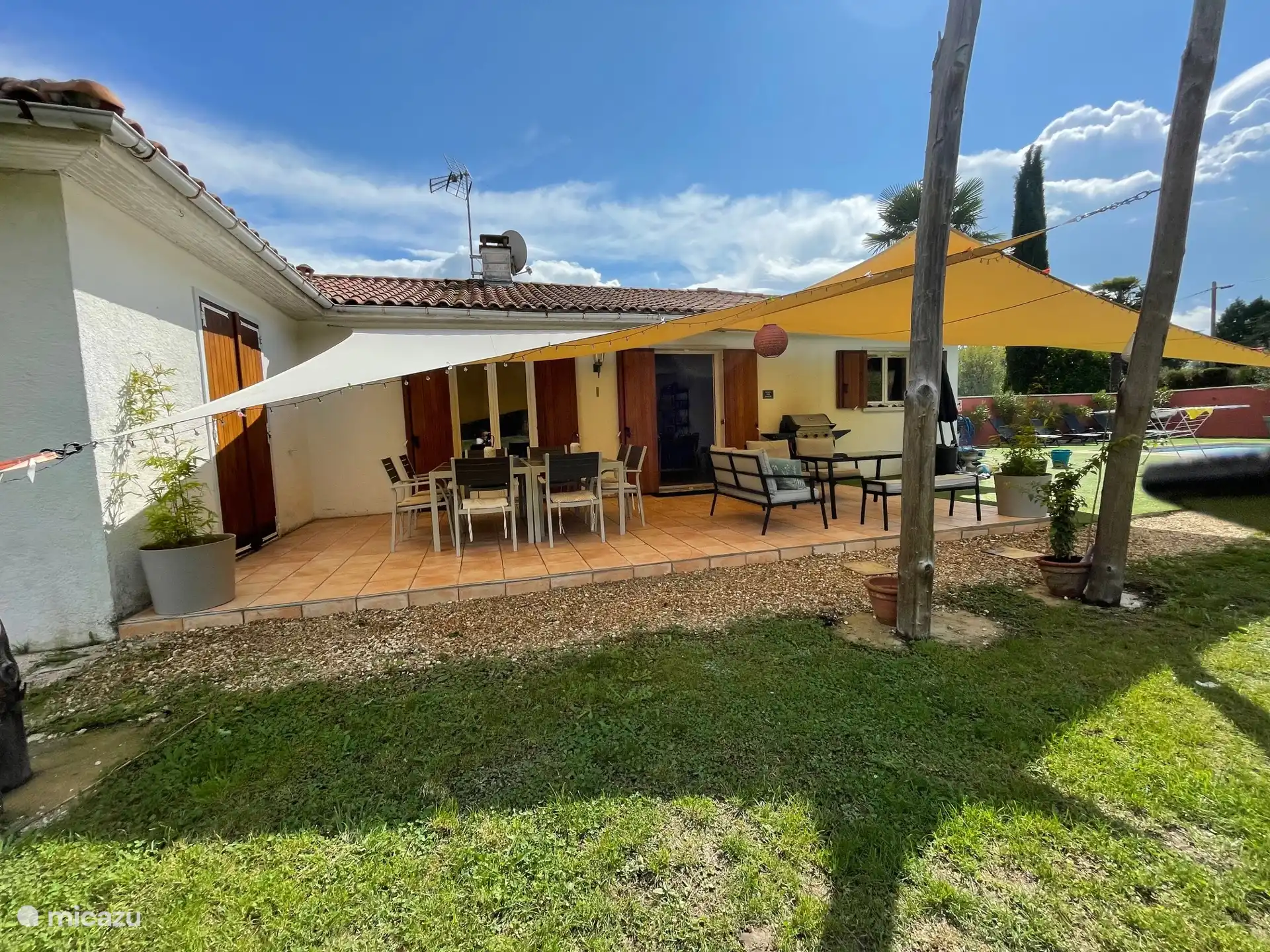 achterkant woning met groot (overdekt) terras en buitentafel voor 8 personen