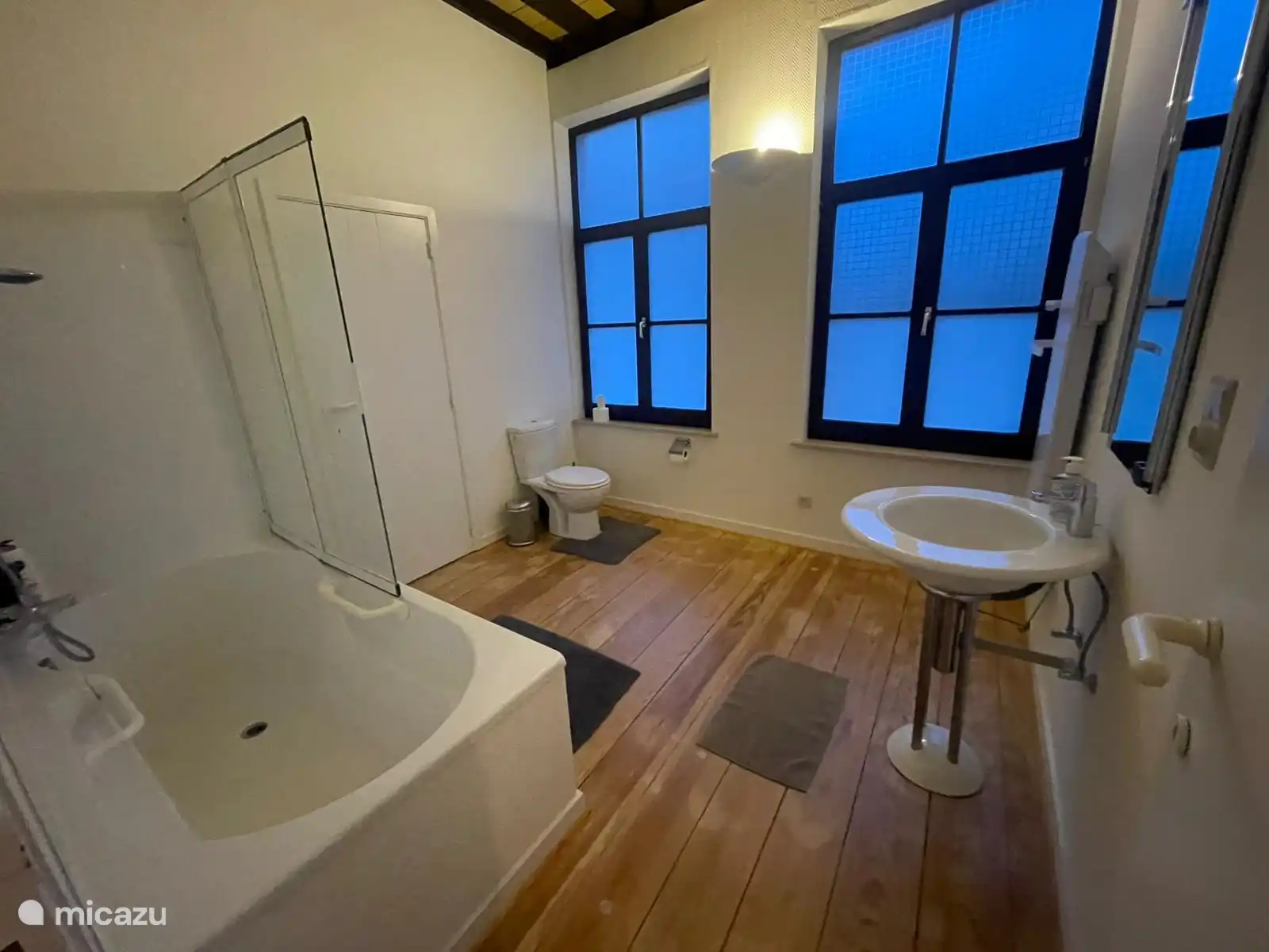 Ein geräumiges Badezimmer mit Badewanne und Dusche, WC und Waschbecken. 