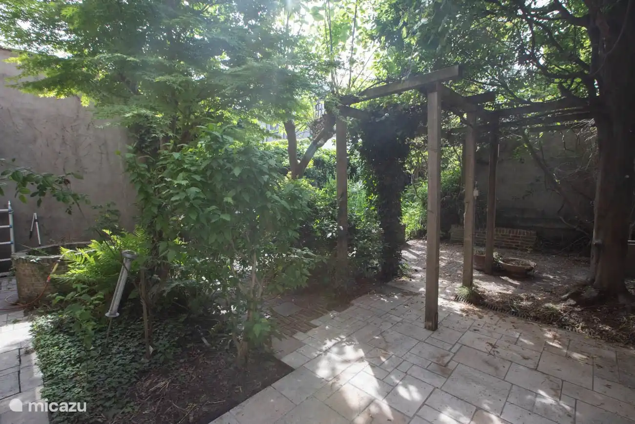 Im hinteren Bereich befindet sich ein grüner Stadtgarten mit Hängematte, großem Tisch und Grill. 