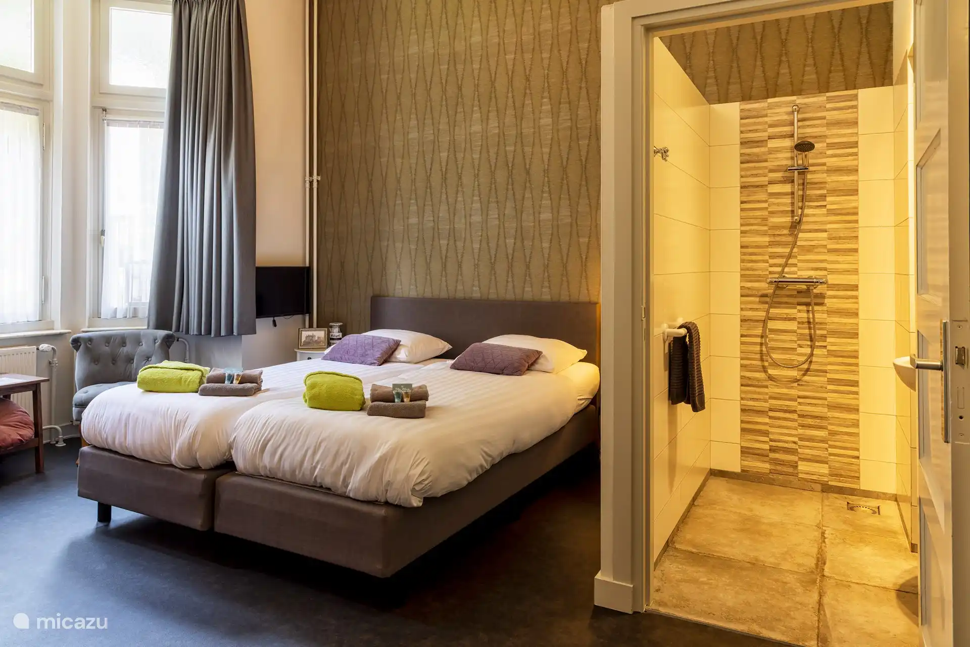 Ein Schlafzimmer mit Dusche, mit Waschbecken, gemütlicher Sitzecke mit Fernseher