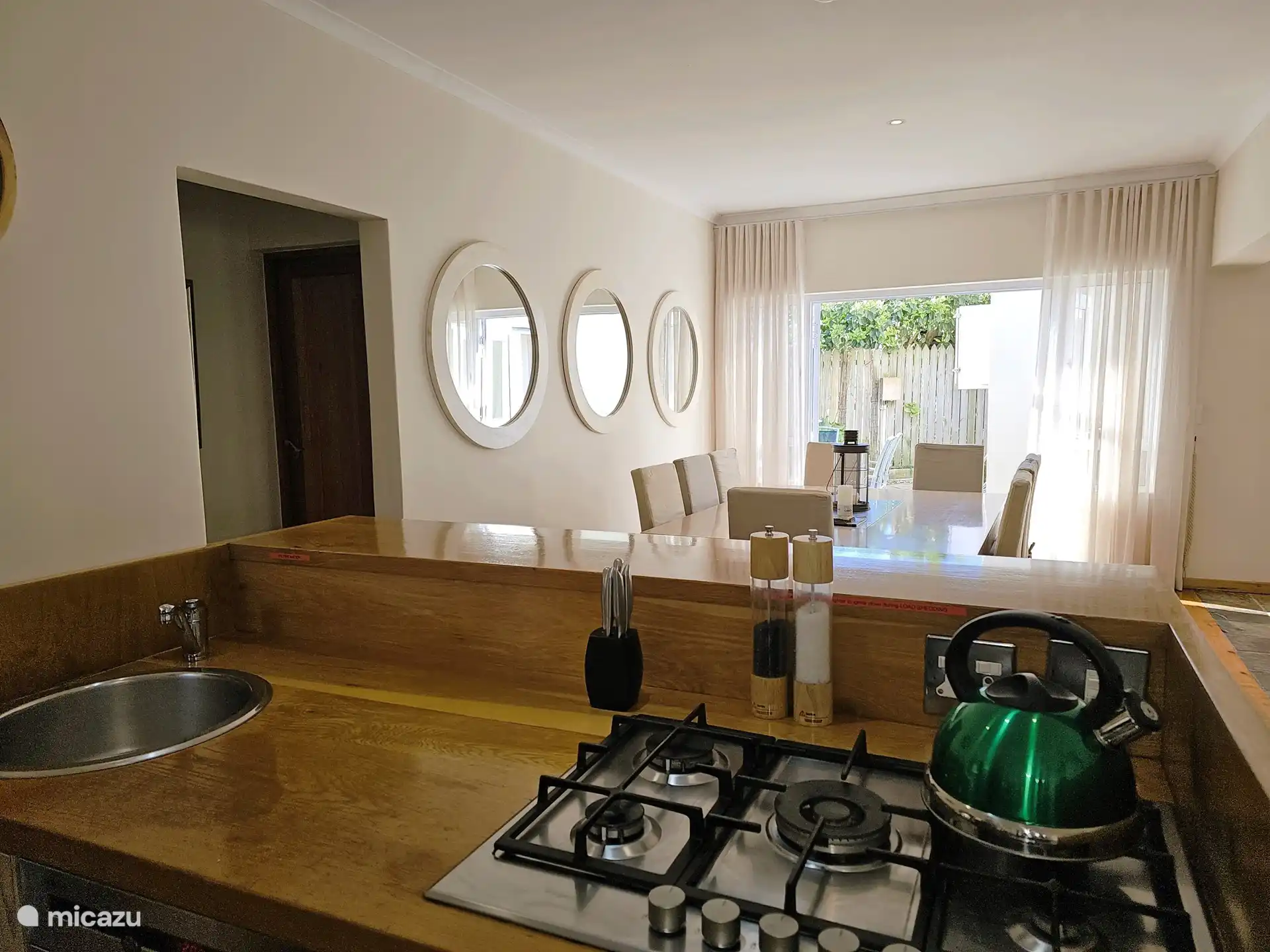 Kitchen, dining table and patio doors to a terrace with outdoor seating and Weber braai