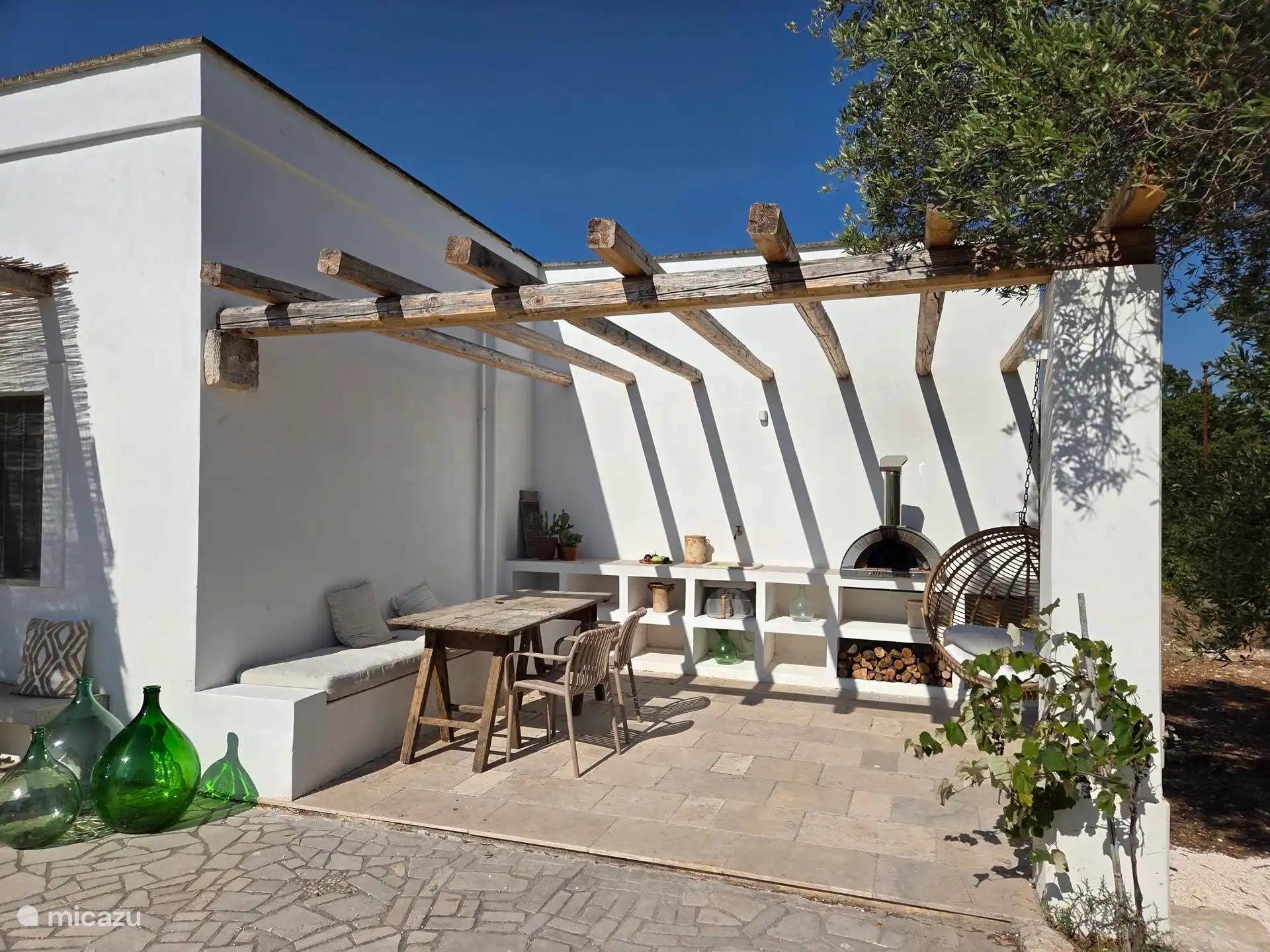 Überblick über die Außenküche und die Terrasse. Mit Lounge-Sofa mit Blick auf den Pool und den Obstgarten.