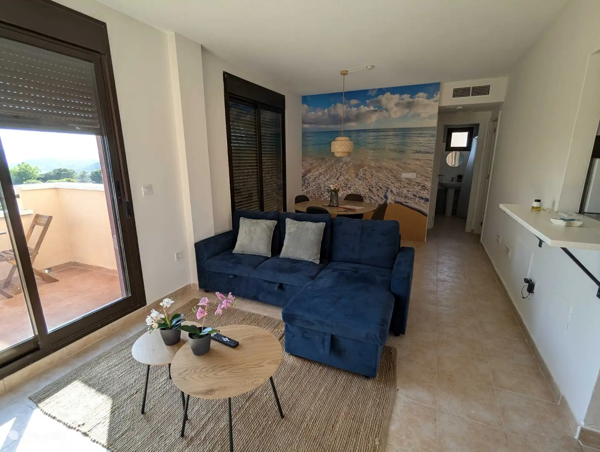 Wohnzimmer mit Schlafsofa und einem Bild des Meeres