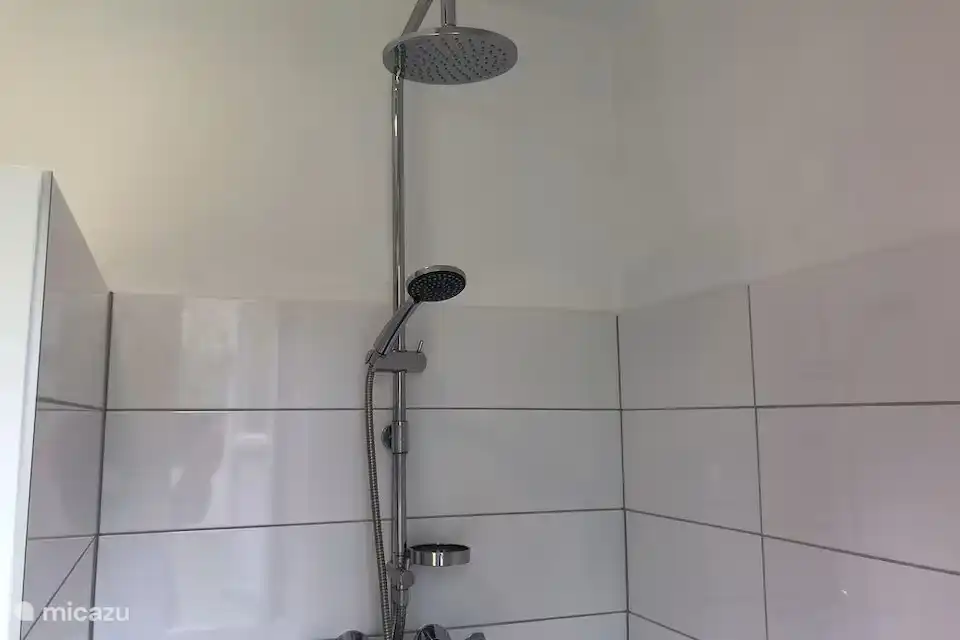 El cuarto de baño cuenta con una amplia ducha y una lavadora.