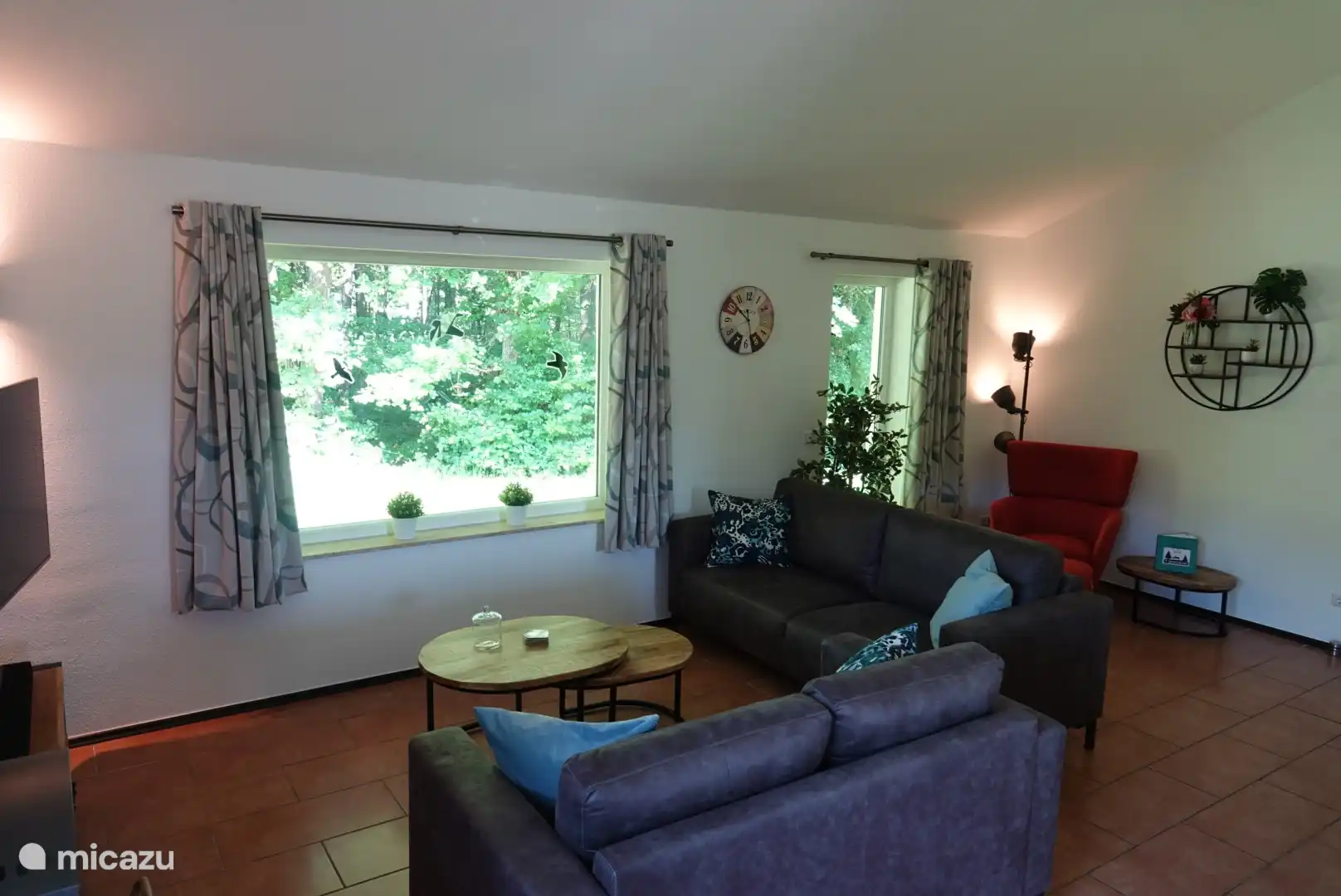 Wohnzimmer mit Holzofen und schönem Blick auf den Wald durch die Fenster