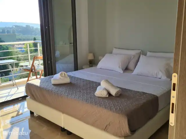 villa huren in Griekenland, Kreta, Heraklion – Het gefluister van de Olijf  Lichte en gezellige slaapkamer met een tweepersoonsbed, airconditioning en directe toegang tot een eigen balkon met een prachtig uitzicht. Ideaal om te ontspannen na een dag verkennen.