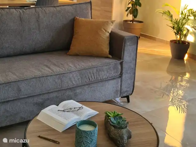 villa huren in Griekenland, Kreta, Heraklion – Het gefluister van de Olijf  De woonkamer straalt warmte en comfort uit, met een zorgvuldig ontworpen ruimte die uitnodigt om te ontspannen en tot rust te komen. Of je nu lekker op de zachte bank kruipt met een boek of geniet van een rustige avond in f