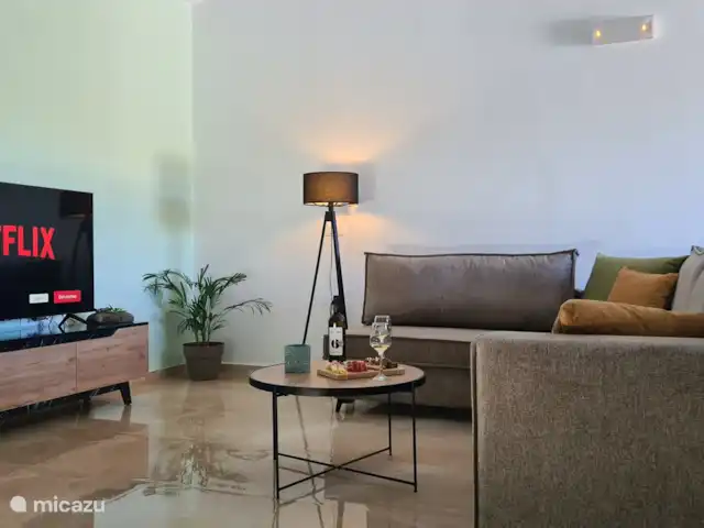 villa huren in Griekenland, Kreta, Heraklion – Het gefluister van de Olijf  De woonkamer straalt warmte en comfort uit, met een zorgvuldig ontworpen ruimte die uitnodigt om te ontspannen en tot rust te komen. Of je nu lekker op de zachte bank kruipt met een boek of geniet van een rustige avond in f