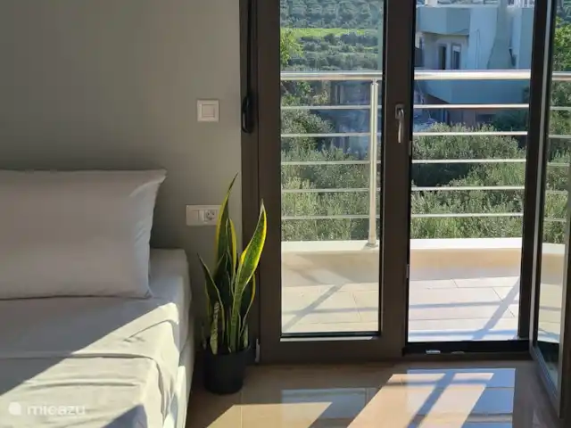 villa huren in Griekenland, Kreta, Heraklion – Het gefluister van de Olijf  Moderne slaapkamer met een minimalistisch design, versterkt door de rustgevende aanwezigheid van kamerplanten - een serene en stijlvolle ruimte om uit te rusten en op te laden.