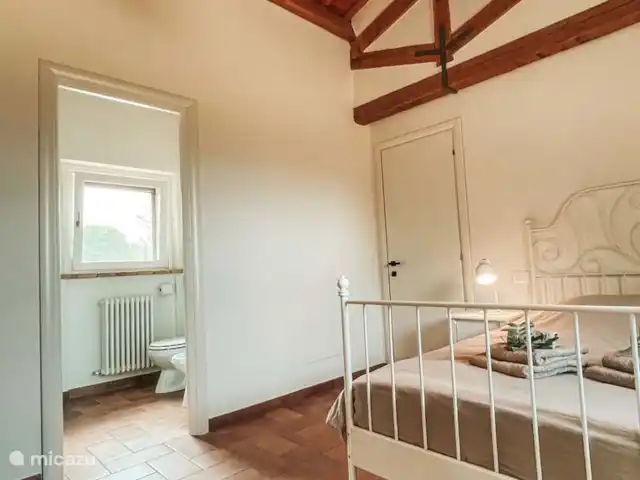 Casa Sette Cipressi | Italie, Marche, Serra de’ Conti  - maison de vacances Chambre (1) dans la Cassetta avec climatisation, lit double et salle de bain attenante avec toilettes, lavabo et miroir et douche. Dans la chambre, il y a une armoire et un coin salon avec 2 chaises et une table.