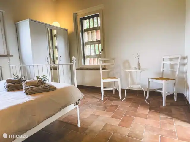 Casa Sette Cipressi | Italie, Marche, Serra de’ Conti  - maison de vacances Chambre (1) dans la Cassetta avec climatisation, lit double et salle de bain attenante avec toilettes, lavabo et miroir et douche. Dans la chambre, il y a une armoire et un coin salon avec 2 chaises et une table.