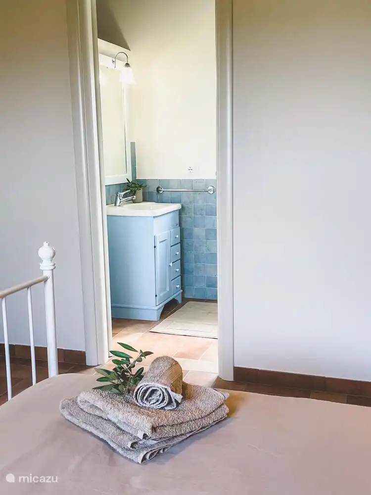 Schlafzimmer (1) in der Cassetta mit Klimaanlage, Doppelbett und angrenzendem Badezimmer mit WC, Waschbecken und Spiegel und Dusche. Im Zimmer gibt es einen Kleiderschrank und eine Sitzecke mit 2 Stühlen und einem Tisch. 