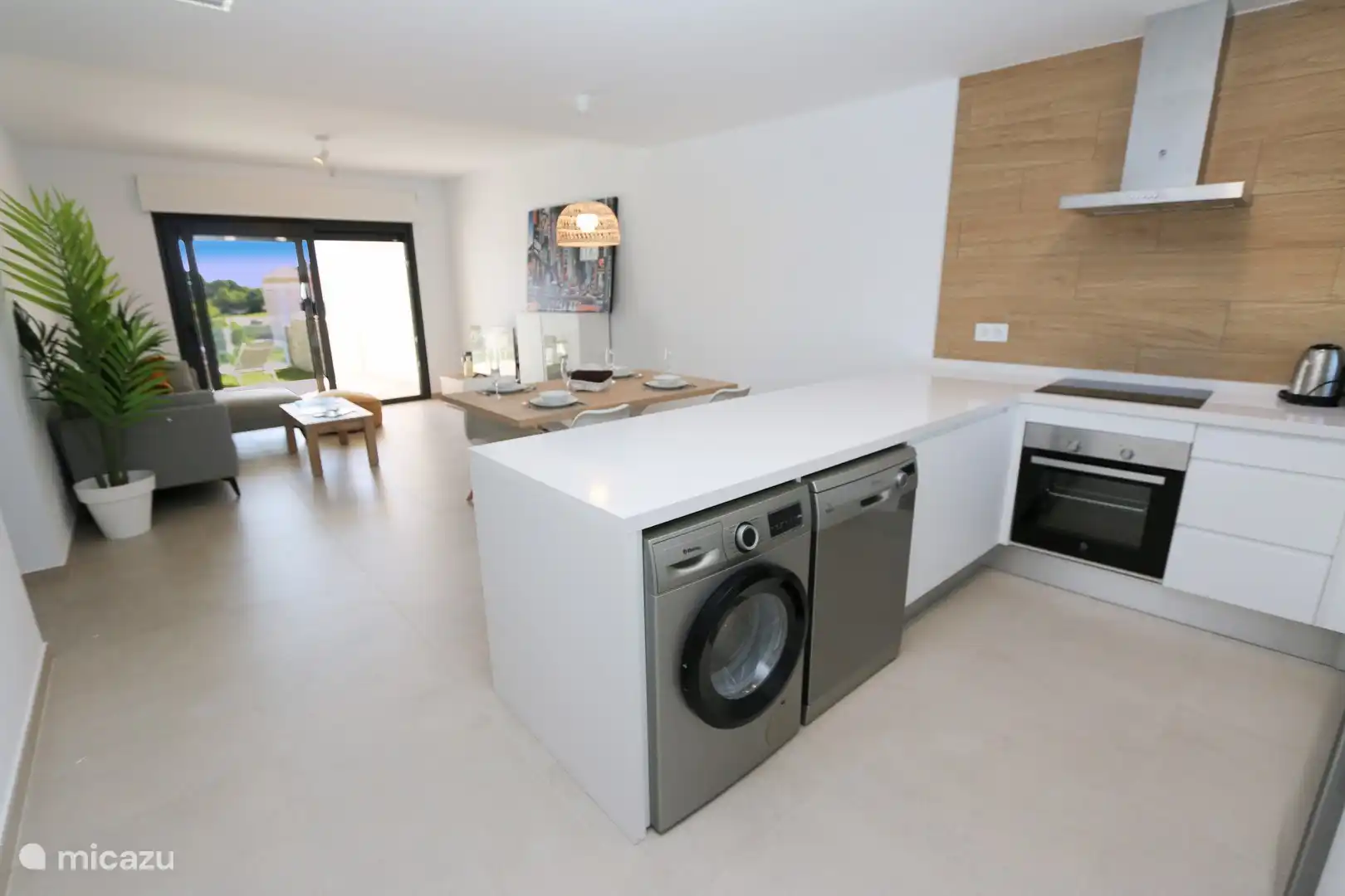 Die moderne Küche ist mit Geschirrspüler, Waschmaschine, Backofen und anderen Geräten ausgestattet.