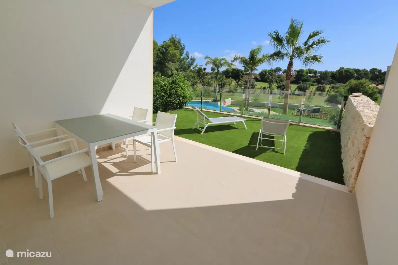 Die Innenterrasse mit Gartentisch und die grüne Terrasse mit Sonnenliegen.