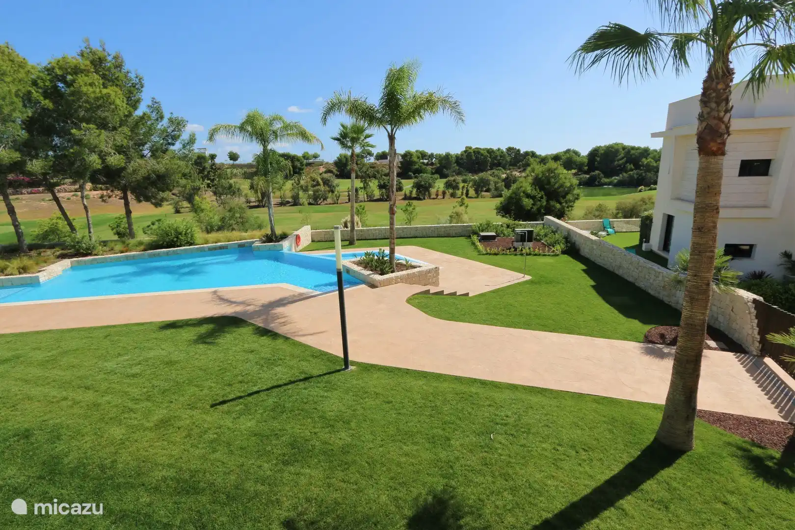 Zugang und Übersicht über den Gemeinschaftspool mit gemeinschaftlicher Liegewiese.