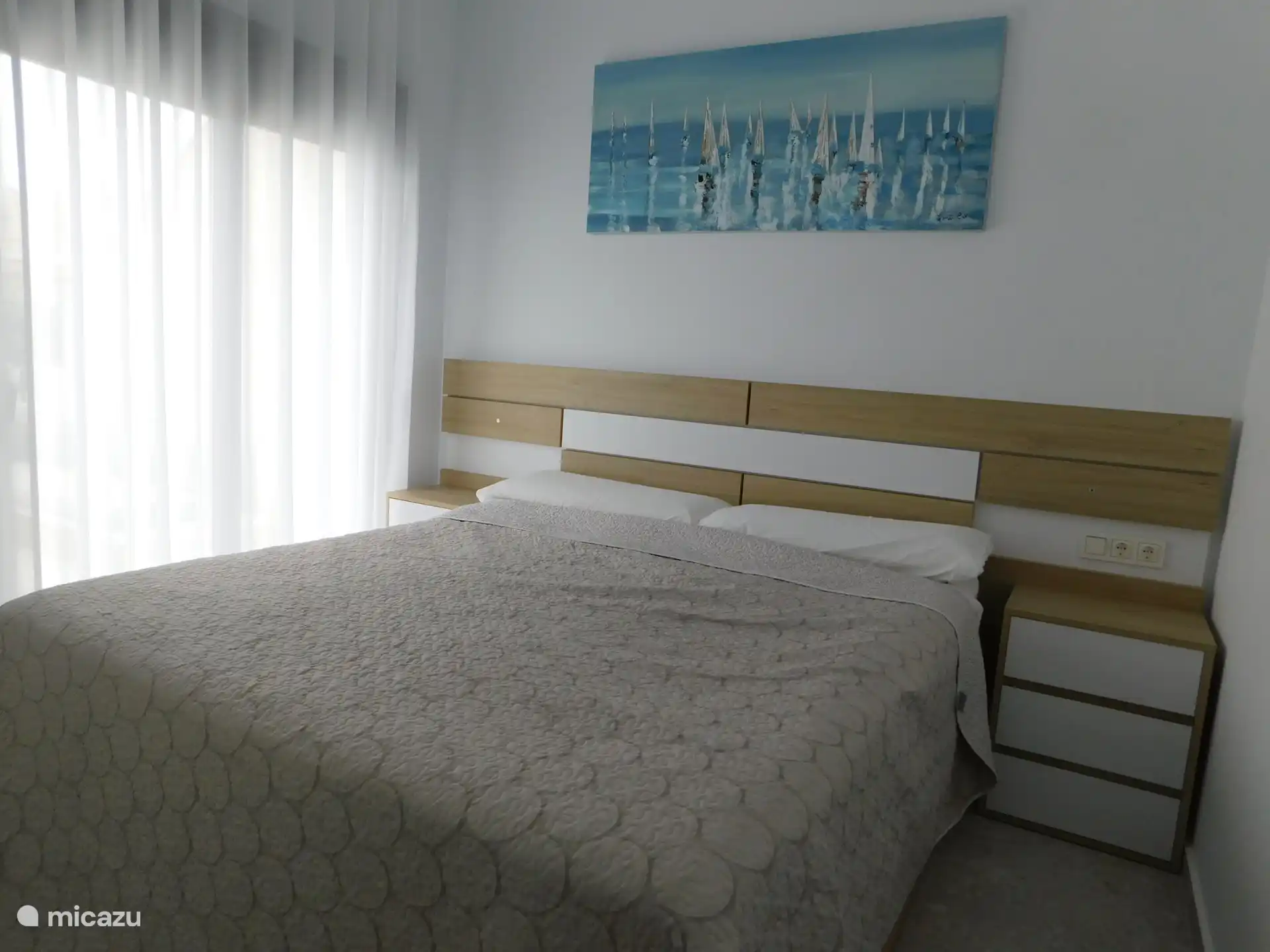 Mittleres Schlafzimmer mit geräumigem Doppelbett, geräumigen Kleiderschränken und Schiebetüren zur direkt hinteren Terrasse mit Blick auf den Pool 