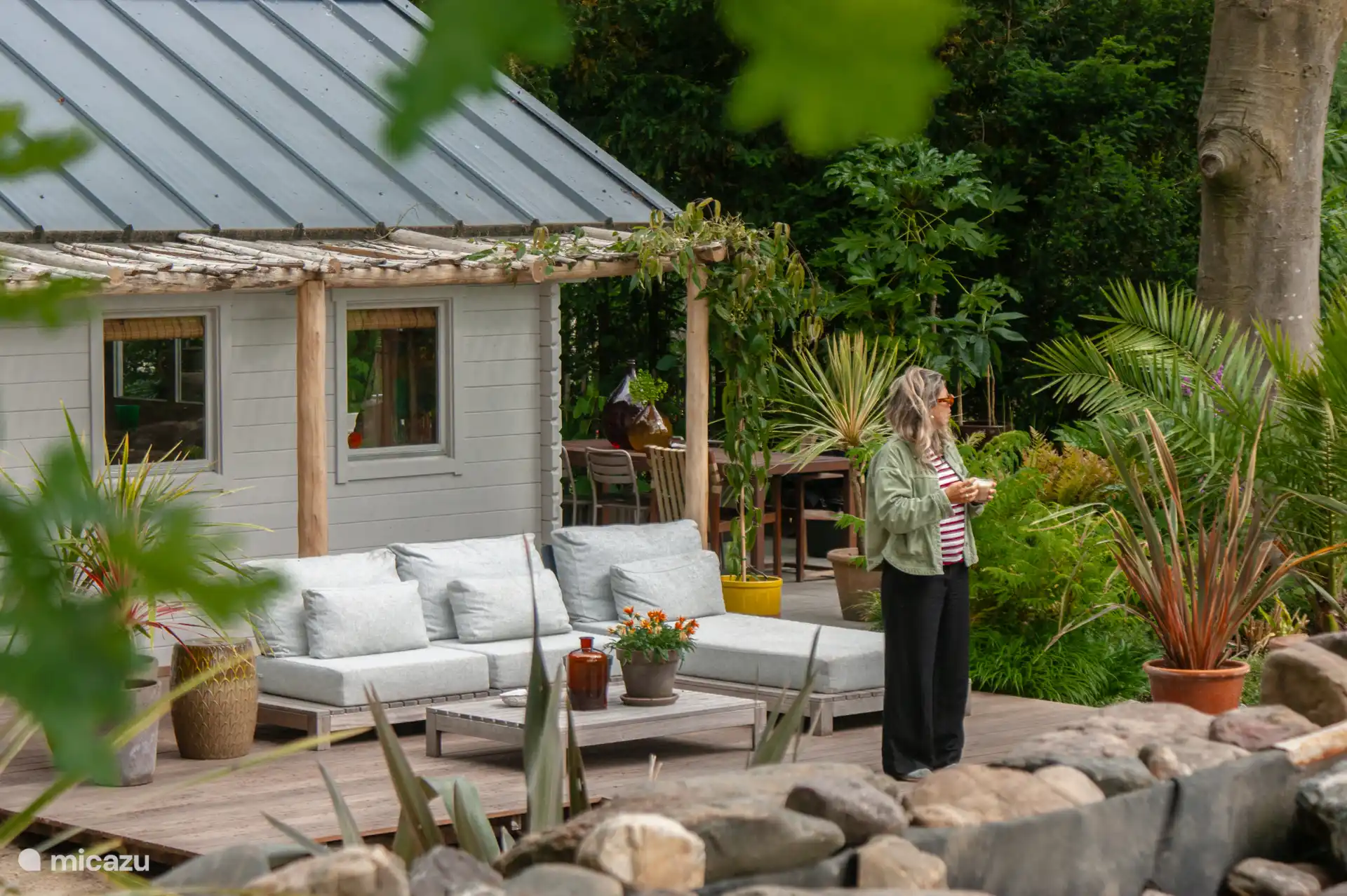 Geräumige Veranda mit großzügigem Lounge-Set und Blick auf den Schwimmteich und die Wiese.