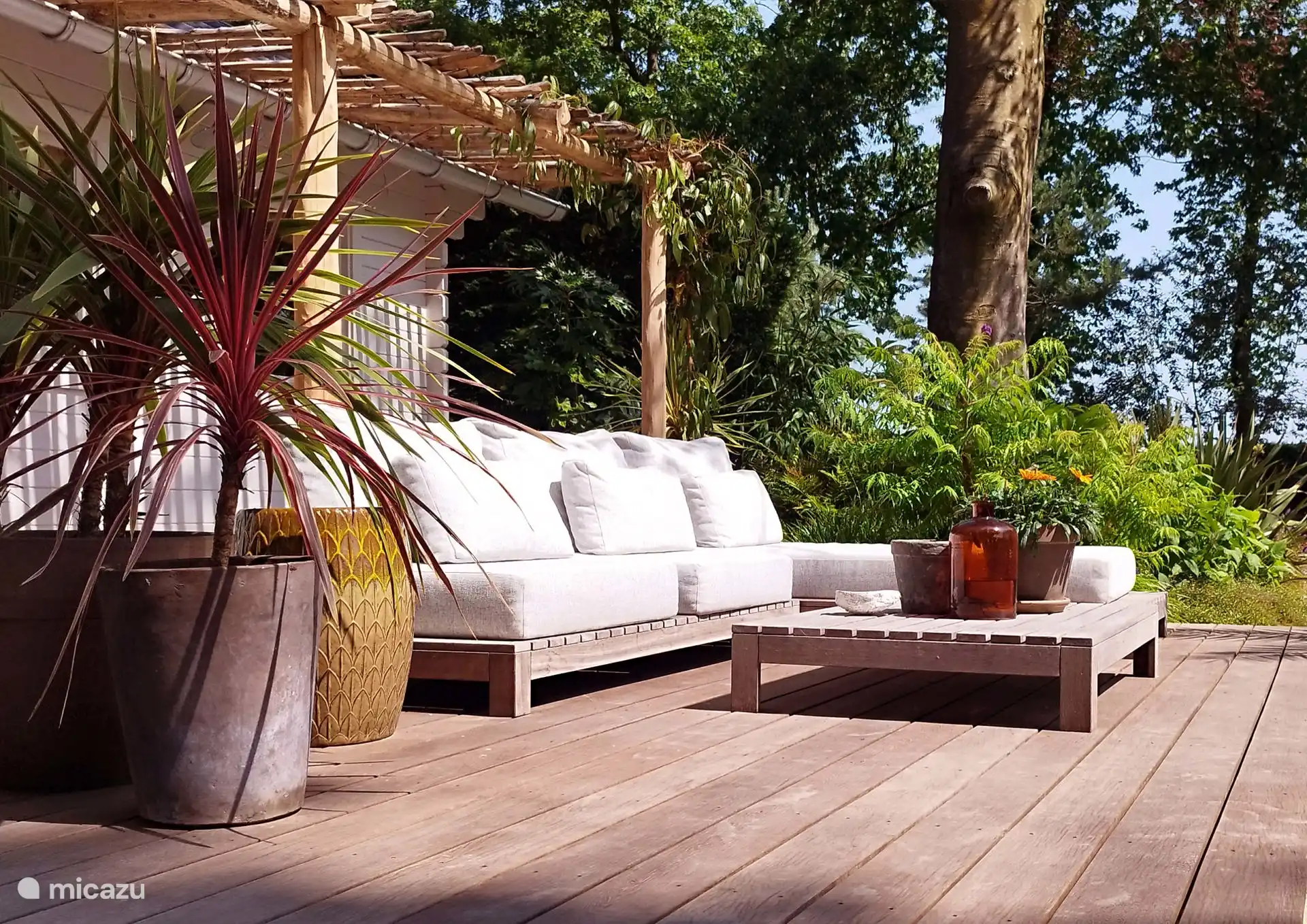 Geräumige Veranda mit großzügigem Lounge-Set und Blick auf den Schwimmteich und die Wiese.