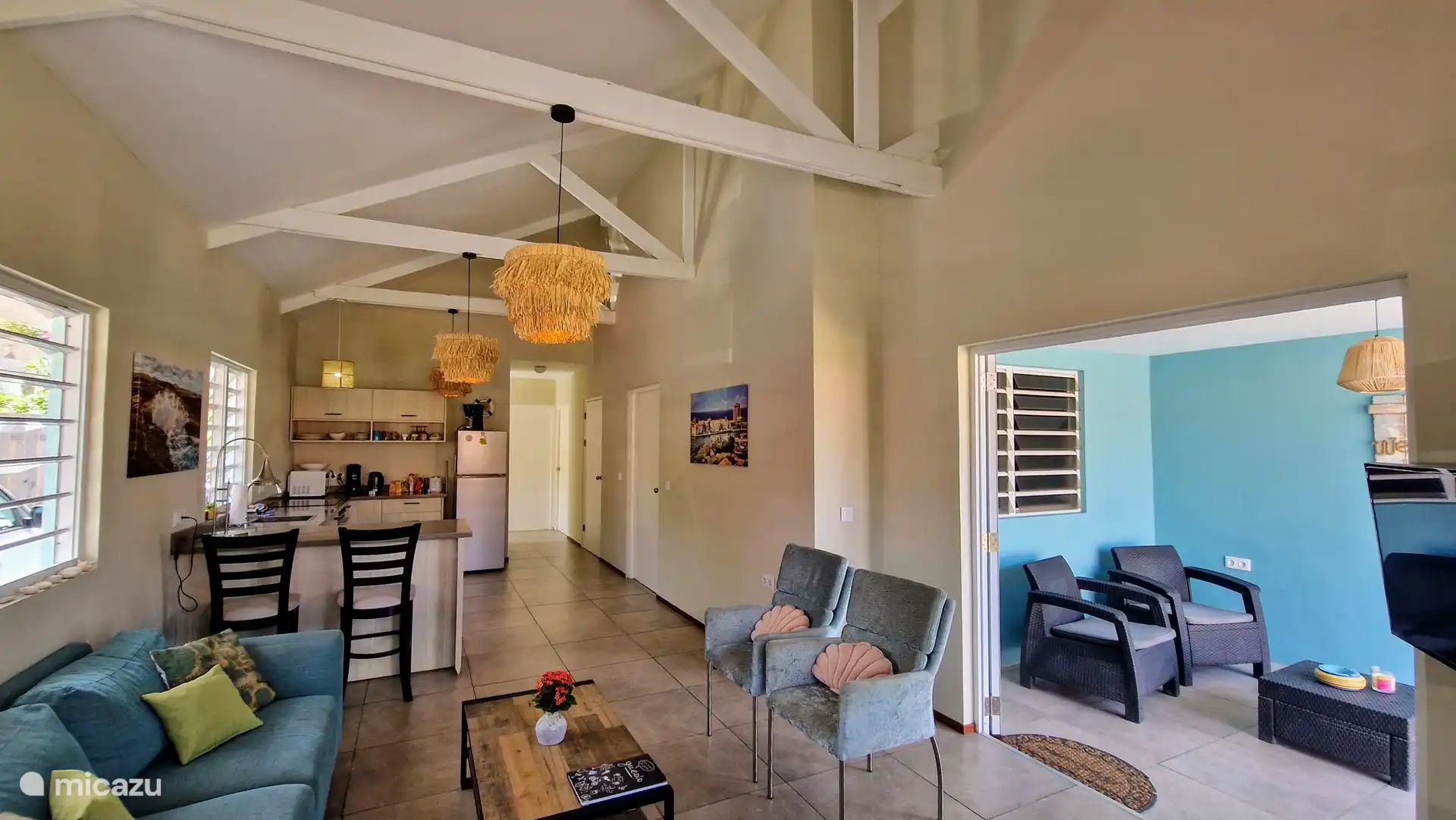 Wohnzimmer mit offener Küche, Terrassentüren zum überdachten Sitzbereich an der Vorderseite