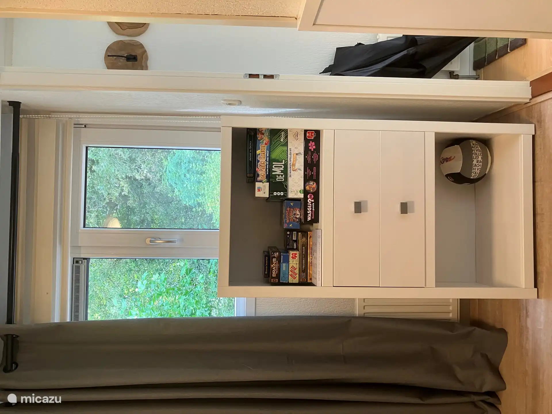 A cupboard with board games, cards, table tennis bats, nets and balls, football and more 