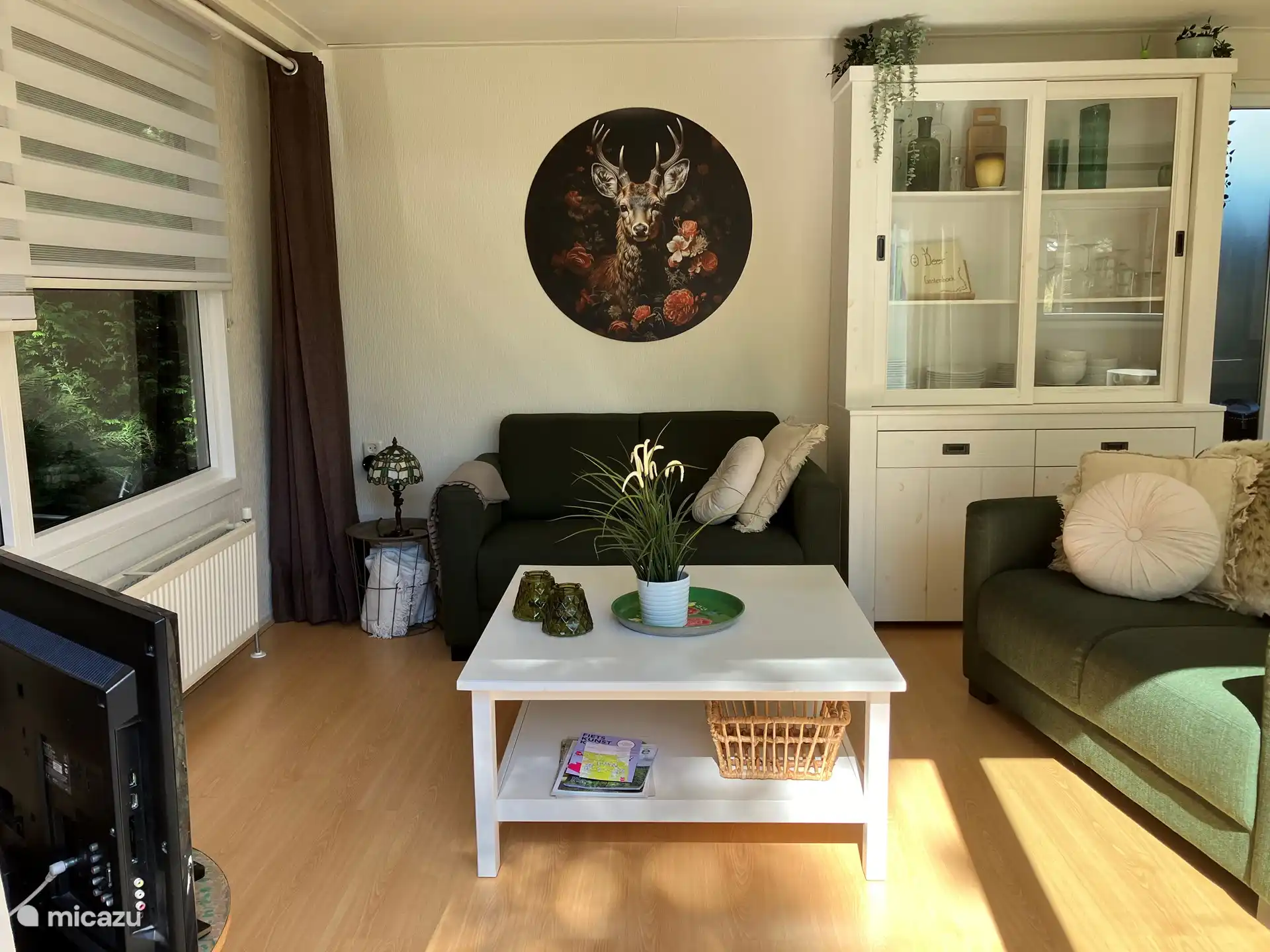 The large window is double glazed and has the same blind as in the kitchen. With the in between curtains you create a warm cozy atmosphere. The large coffee table offers space for everything you want to have at hand and for children to color and play with