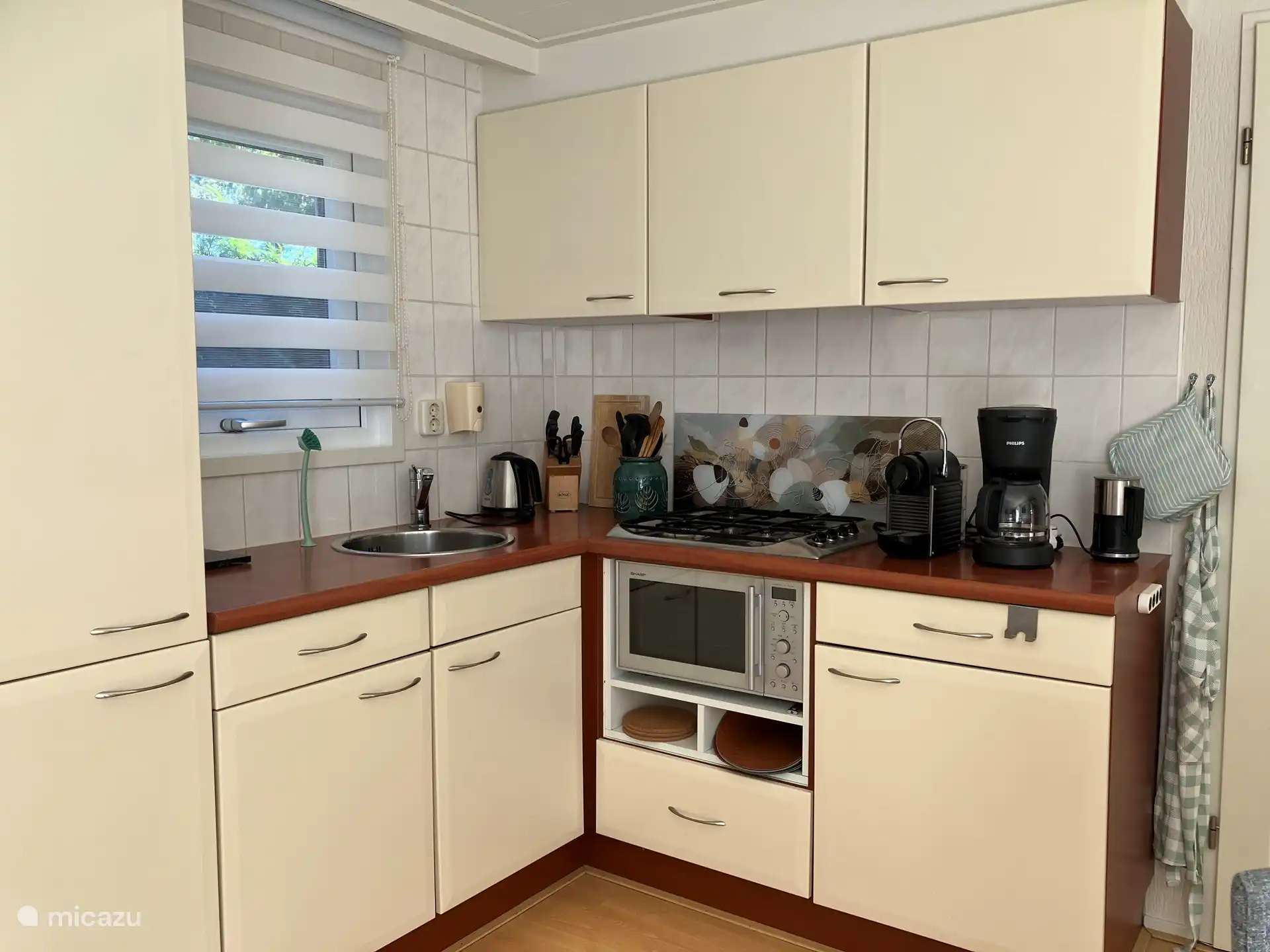 You can see the 4-burner stove, the combi microwave, and several cabinets. This is where all the pots, pans, cups and cutlery are located. Under the counter you will find kitchen linen, dishcloths and all cleaning and dishwashing products. A drainer, dustpan and dustpan and enough space for your own groceries