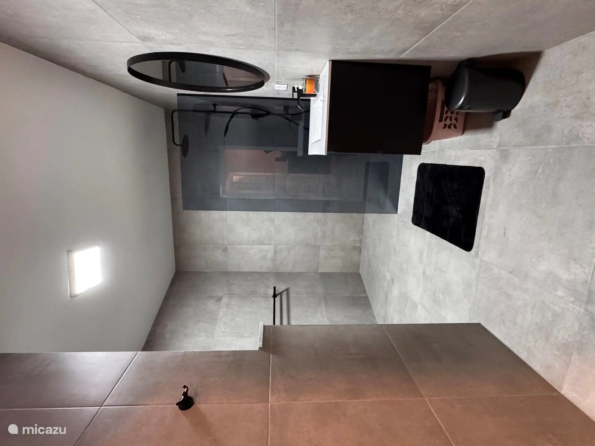 Badezimmer mit Dusche, Waschbecken und WC.