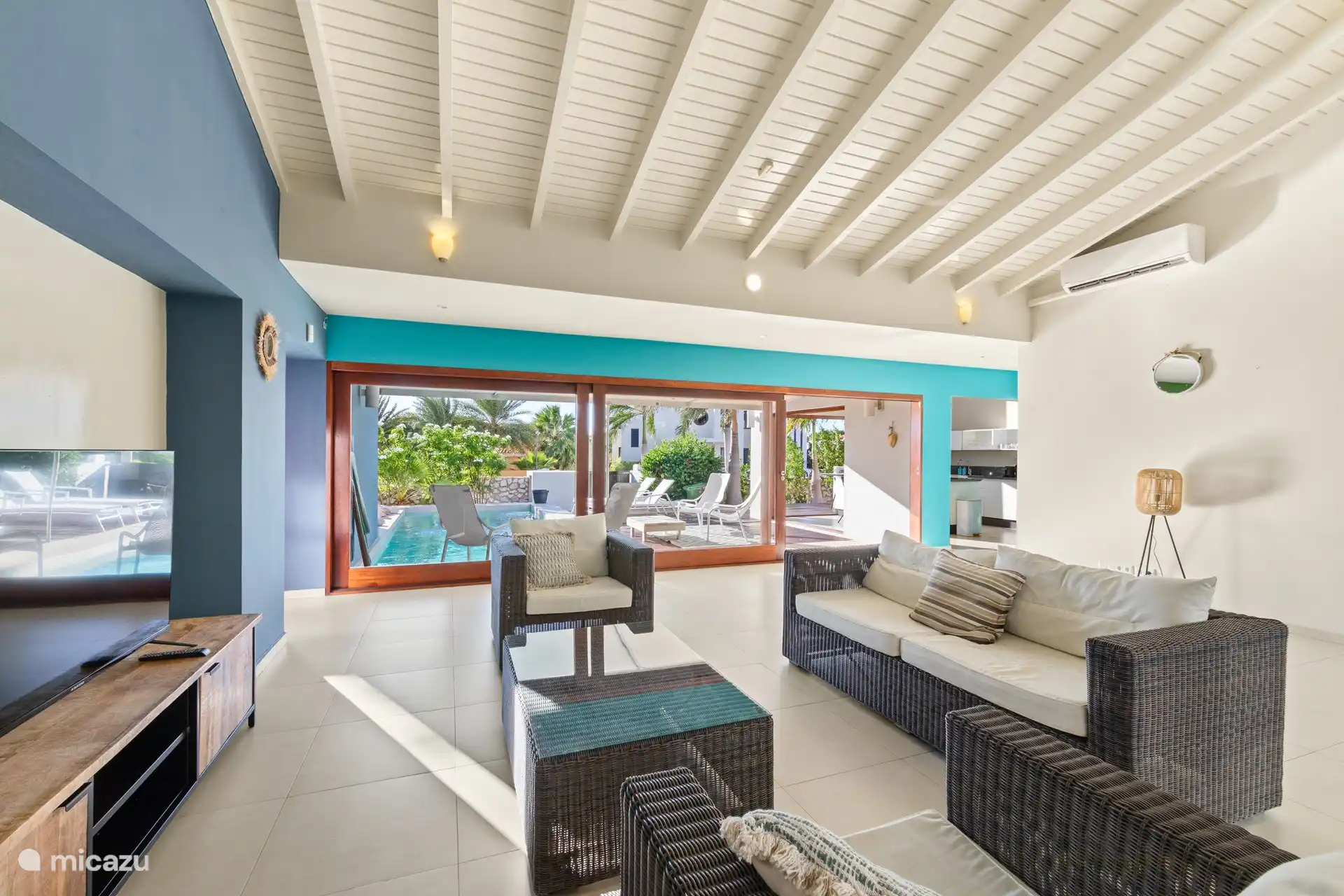 Living room with a view of the kitchen (right) and swimming pool