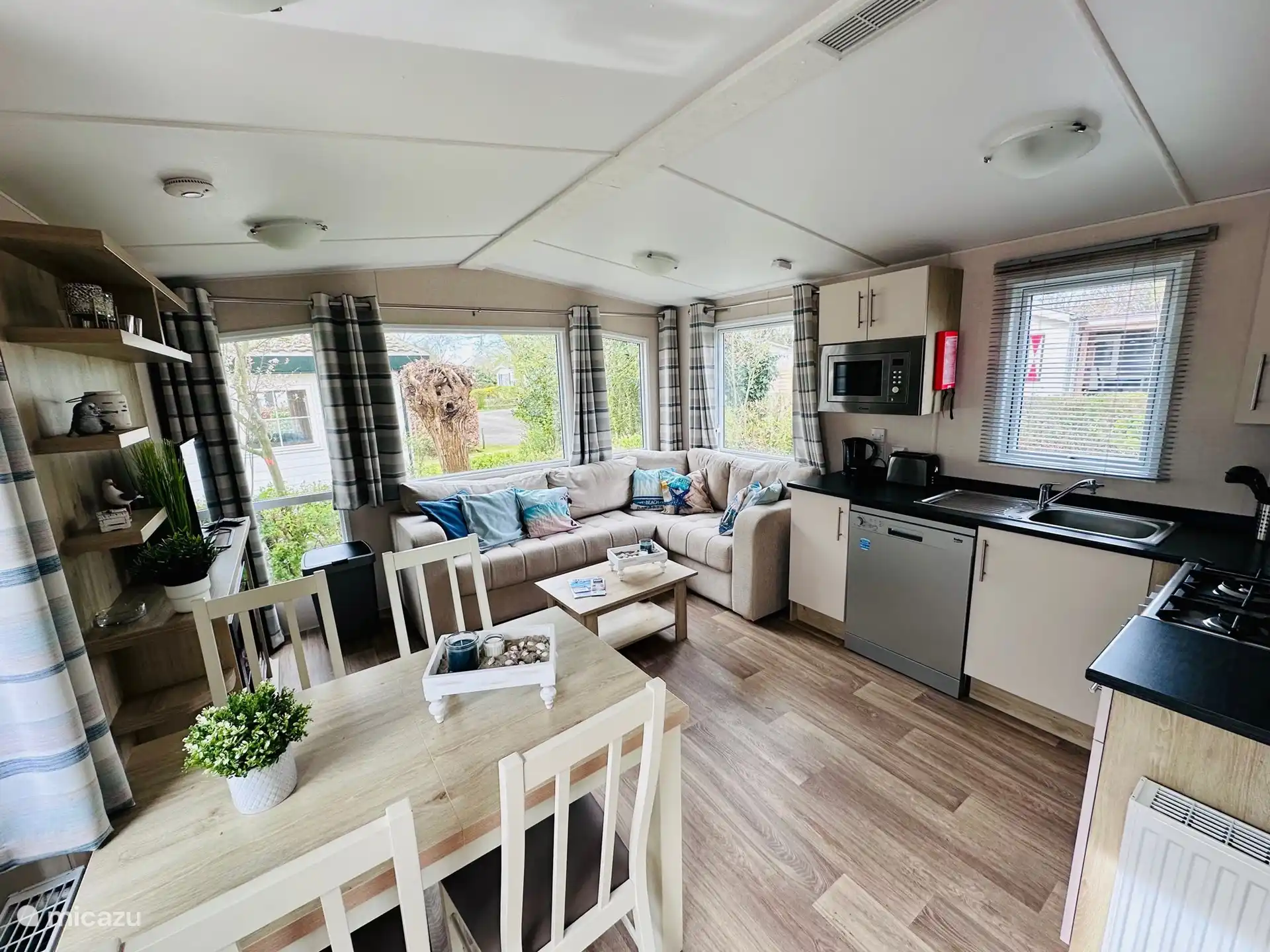 Liebevoll dekoriertes Wohnzimmer mit einer gemütlichen Couch und einem Elektrokamin für kühlere Tage