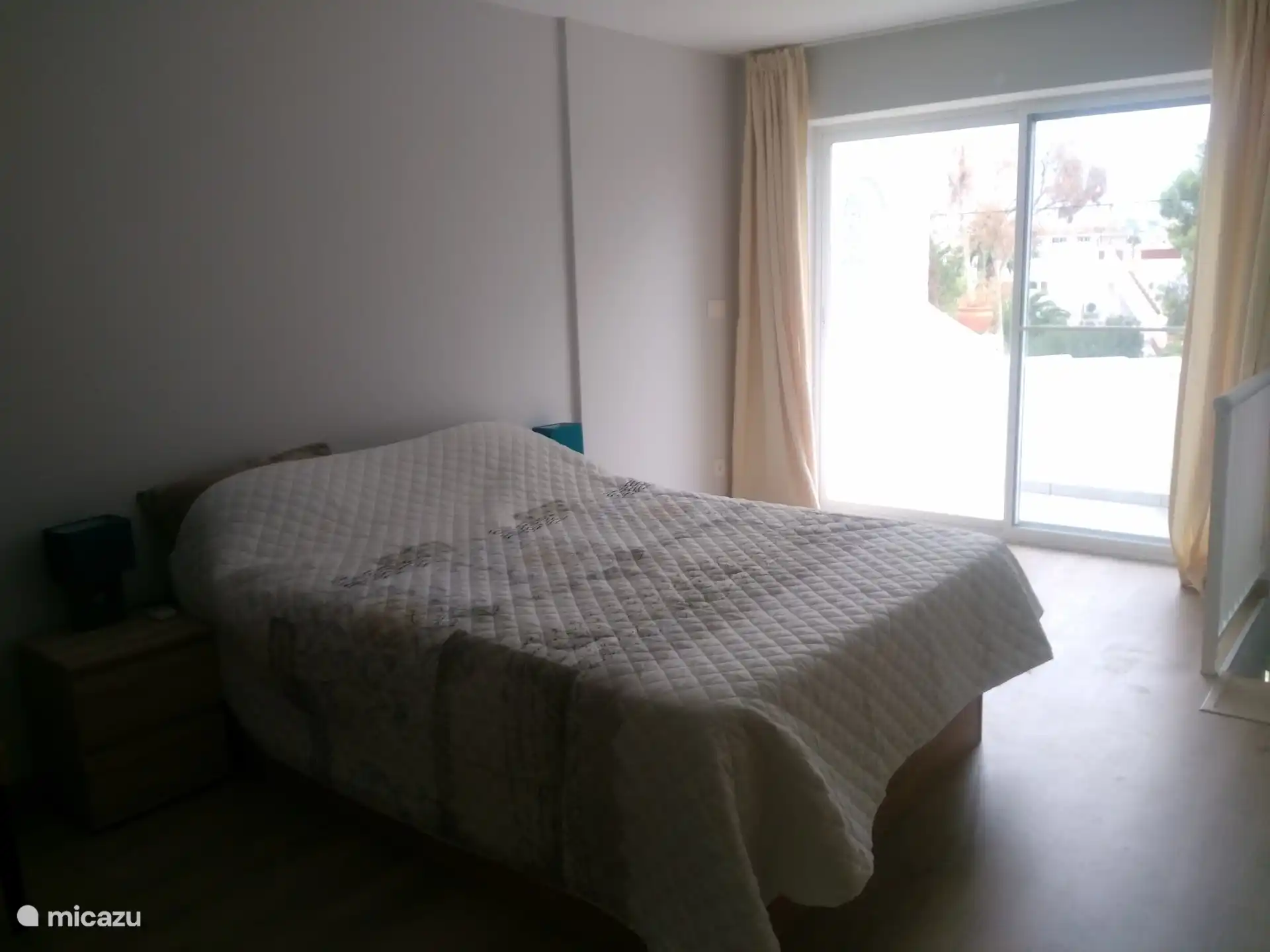 Chambre avec lit double pris sous un angle différent, porte du disque donnant sur la terrasse et vue sur la montagne