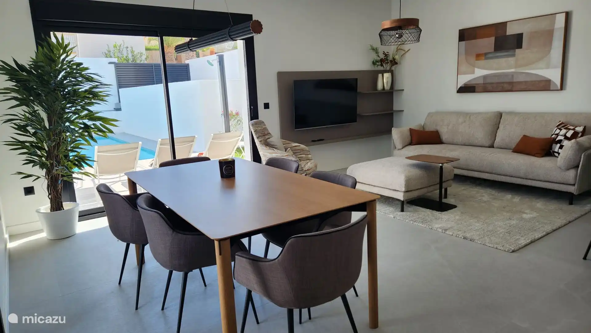 Salon confortable avec un canapé confortable et des fauteuils. Ensuite, il y a la table à manger avec 6 chaises. 