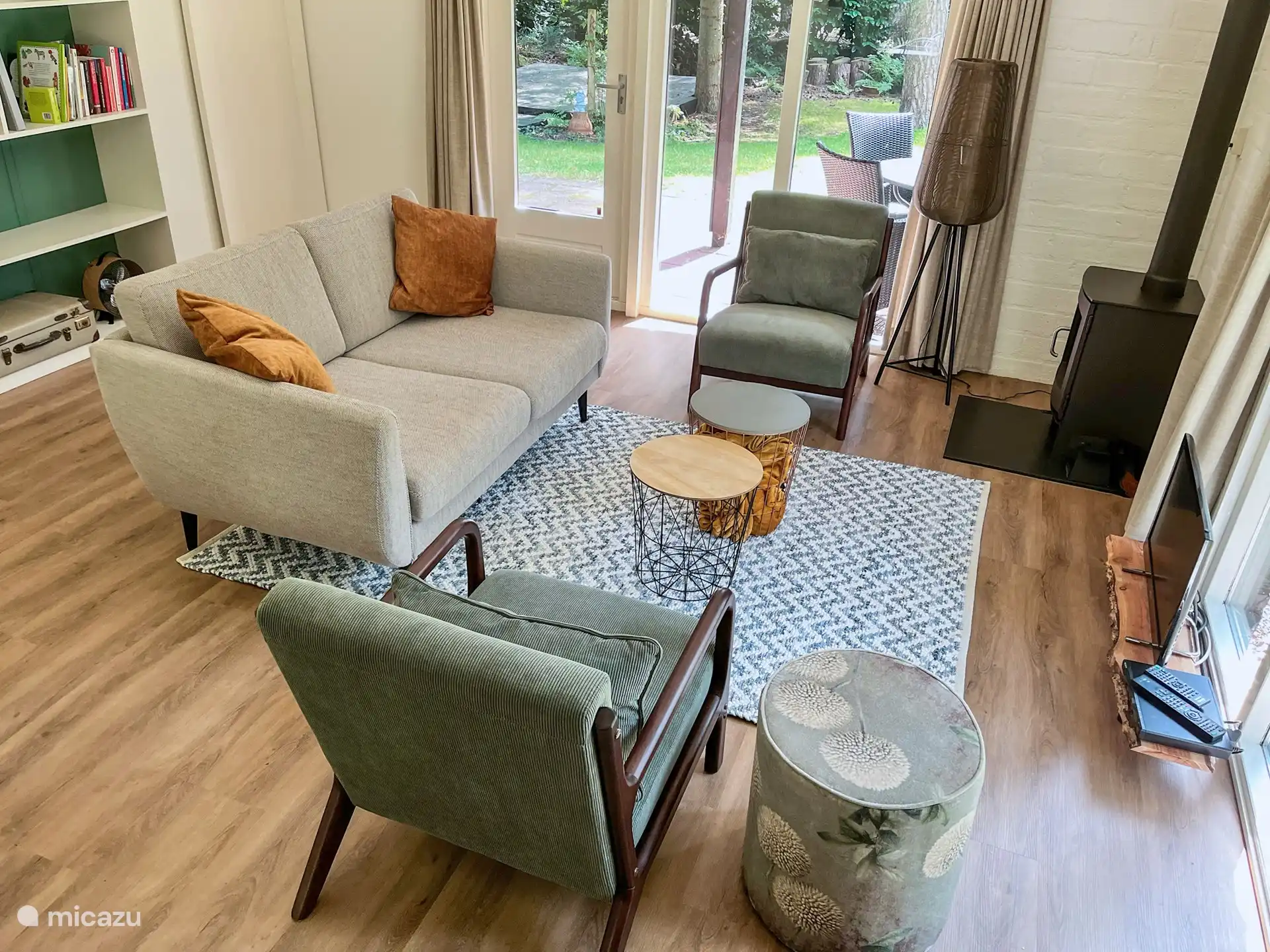 Wohnzimmer mit 2-Personen-Sofa, 2 Sesseln, Smart-TV, Spielen, Büchern und einem Holzofen.