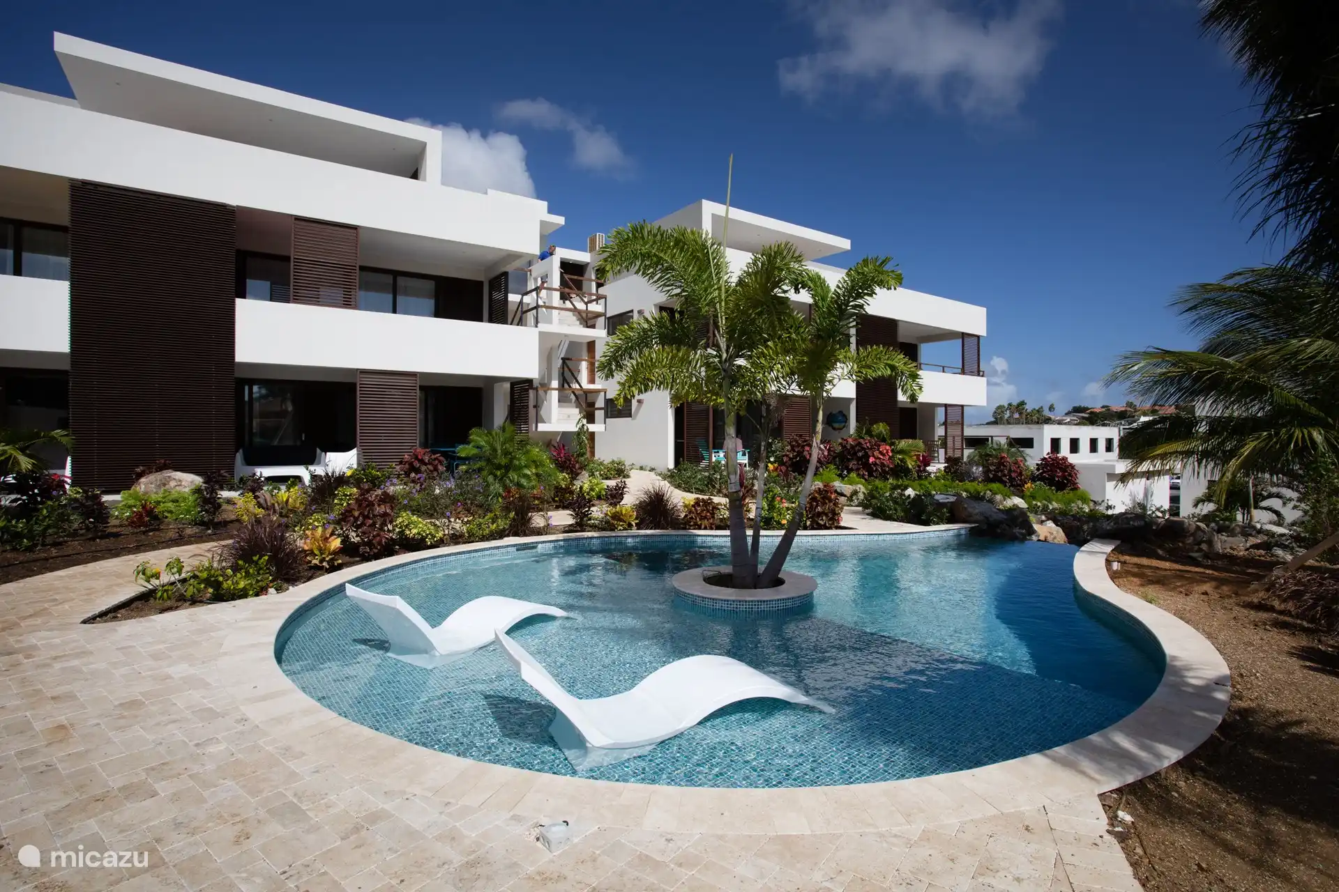 Heerlijk tropisch zwembad met ligstoelen in het water