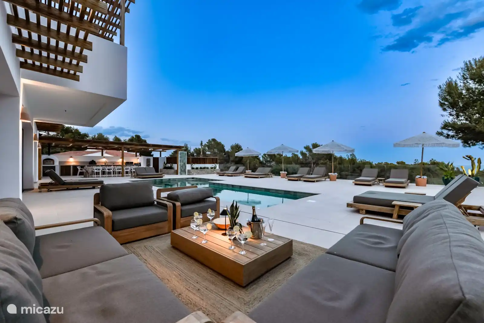 Der Loungebereich aus Teakholz verfügt über einen großen Sonnenschirm für ein schönes schattiges Plätzchen.