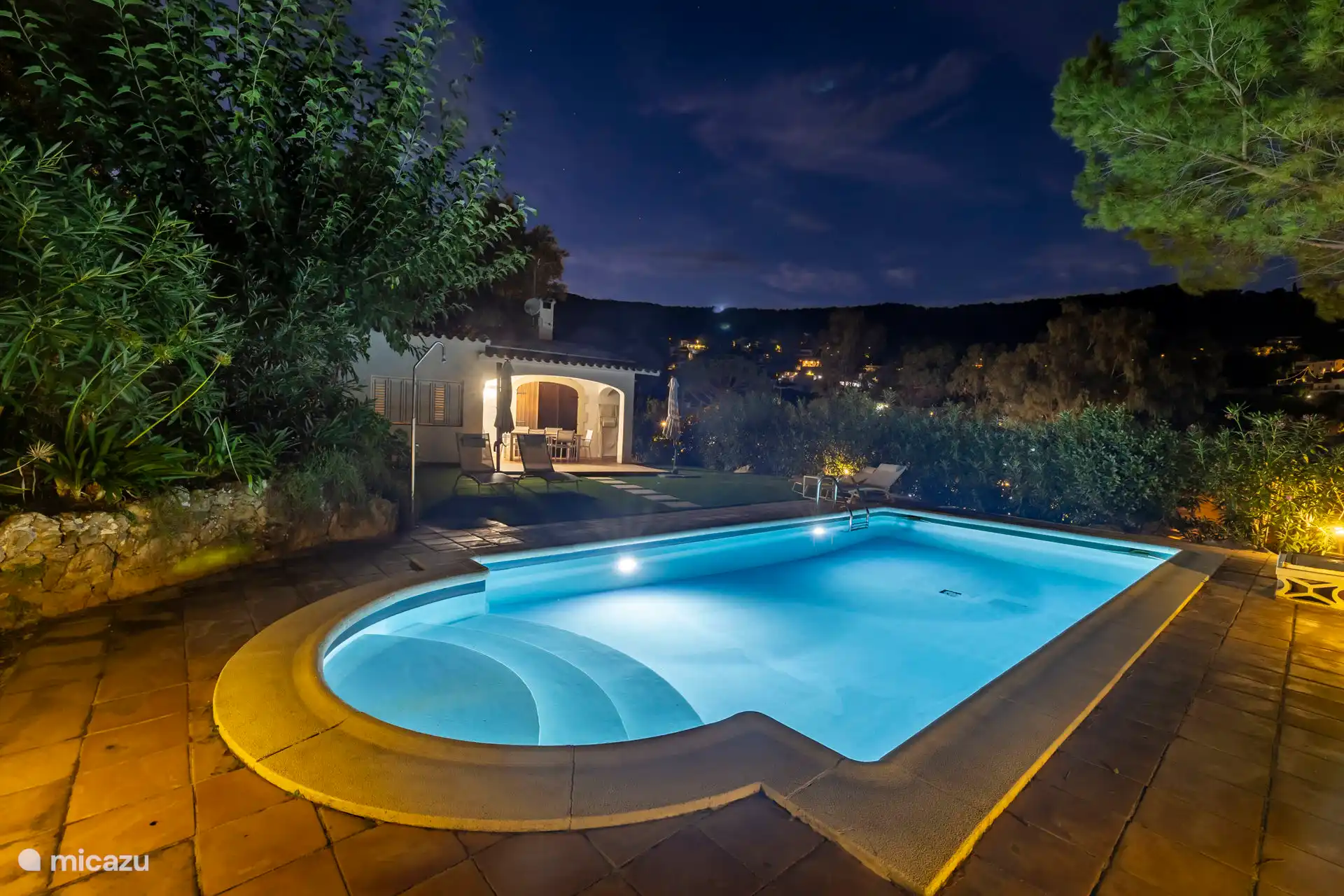 Avondfoto achtertuin met verlicht zwembad