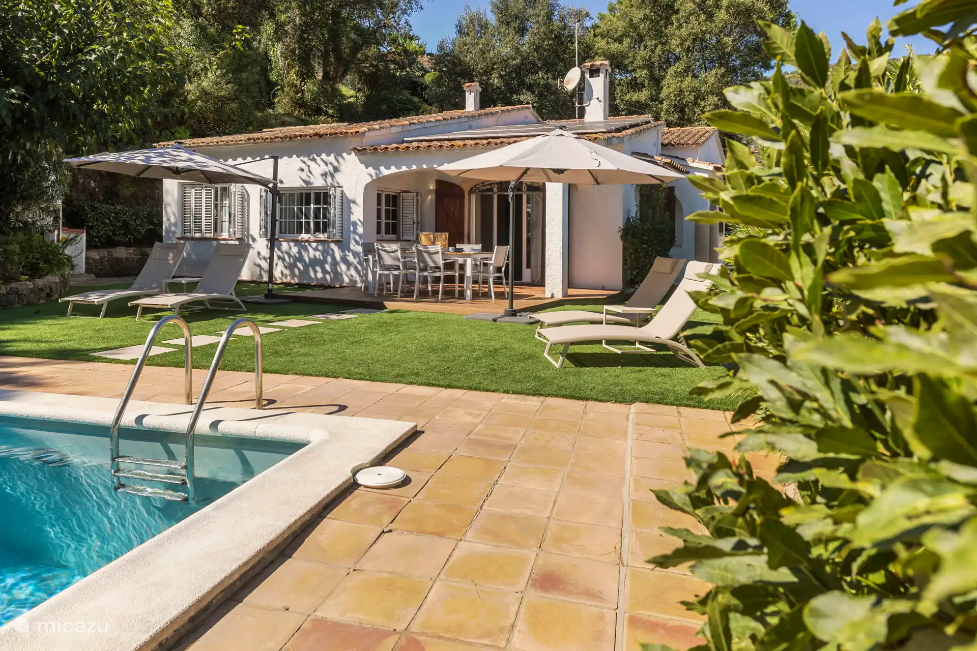 Achtertuin met 2-tal parasols en ligbedden