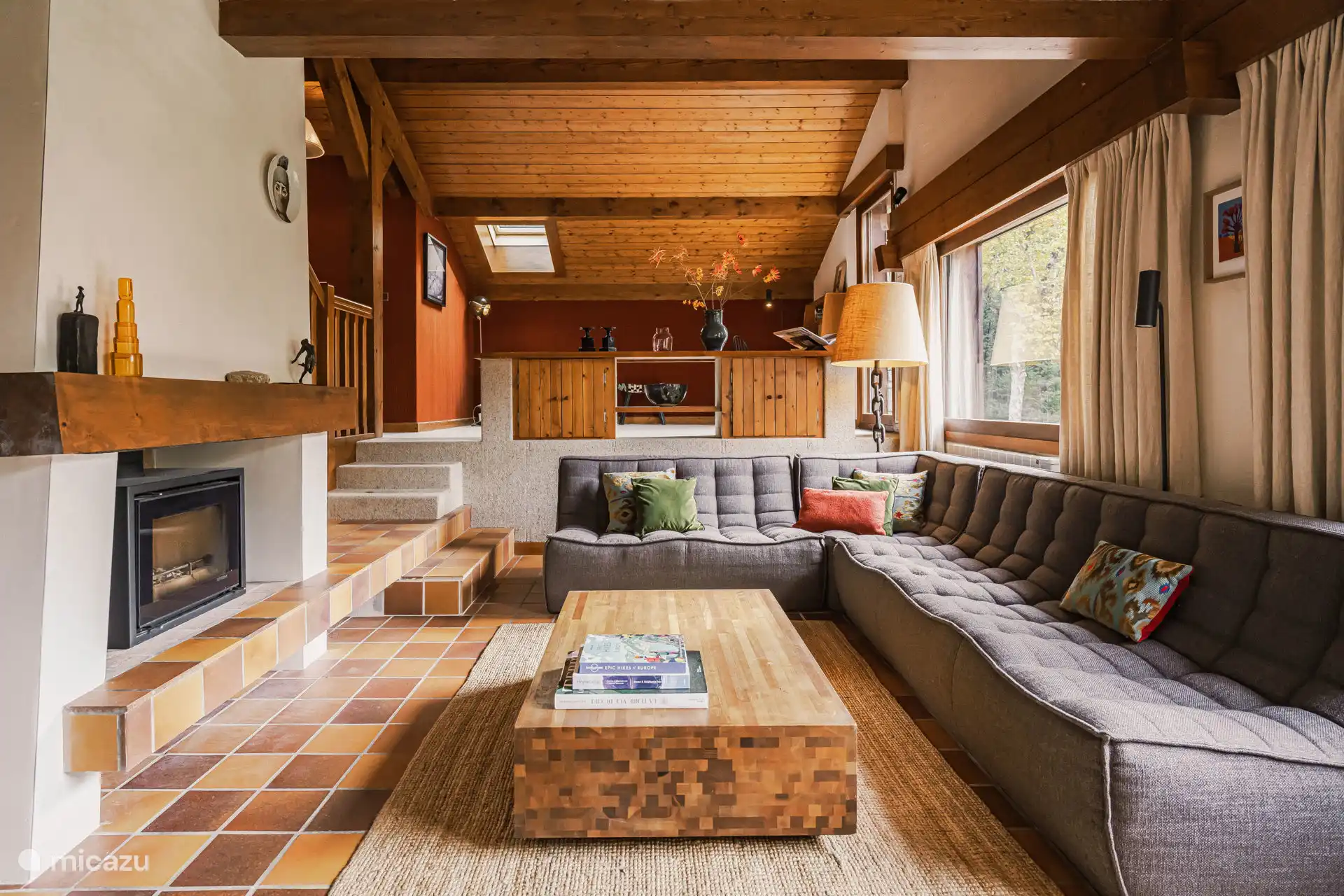 Een ruime zitkamer en moderne zithoek met een houtkachel. 