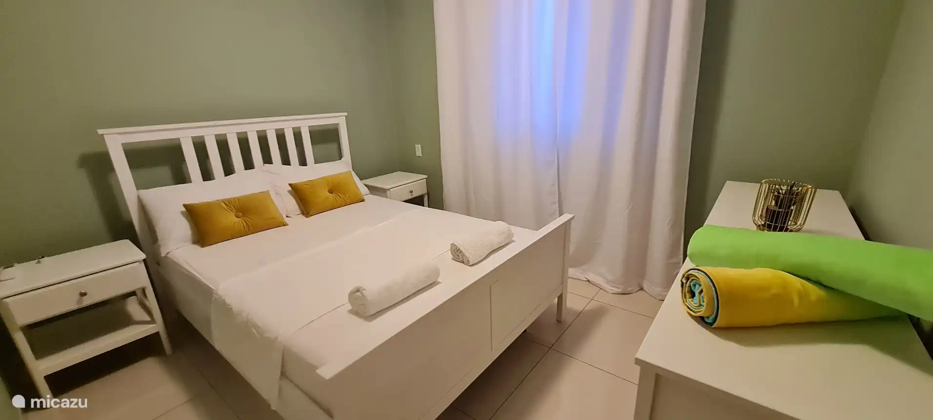 La troisième chambre comprend un lit queen, un dressing à tiroirs pour les vêtements, des tables de chevet et un climatiseur. 