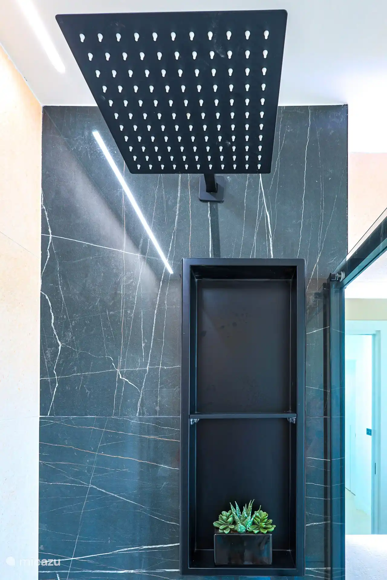 Une salle de bains moderne avec une douche à l’italienne spacieuse, dont la salle de douche est finie avec de belles pierres naturelles