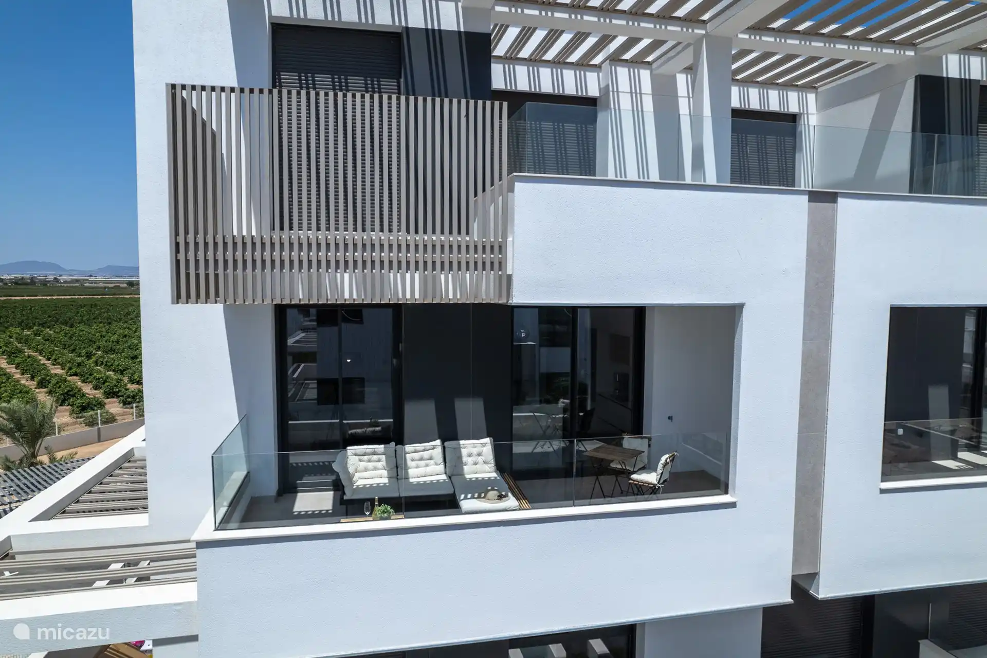 Une vue aérienne d’un balcon moderne. Le balcon est meublé avec un mobilier d’extérieur contemporain, notamment une petite table et un canapé.