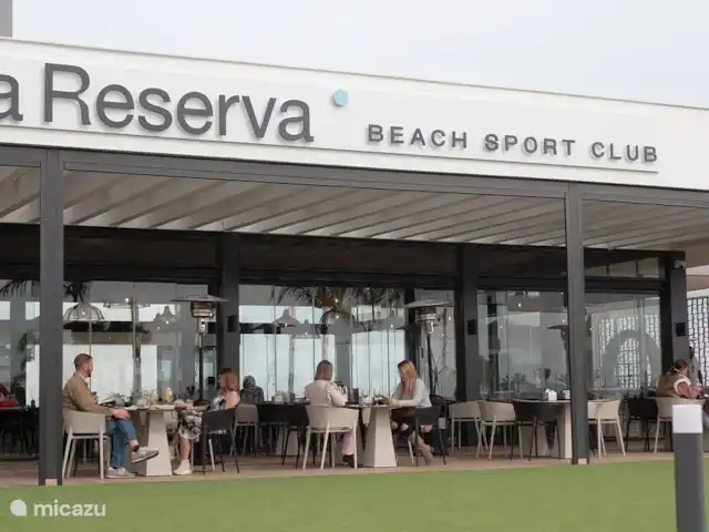 Casa SK Santa Rosalia | Espagne, Costa Cálida, Torre Pacheco - appartement Une photo du Beach Resort Club montre un espace de restauration animé et accueillant au bord de la plage. L’espace est meublé avec des tables en bois élégantes et des chaises confortables, parfaites pour les clients qui souhaitent profiter d’un déjeuner ou d’un dîner tranquille.