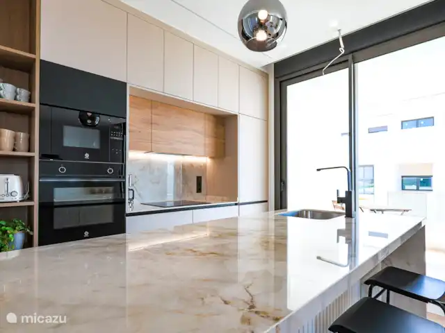 Casa SK Santa Rosalia | Espagne, Costa Cálida, Torre Pacheco - appartement Cette cuisine moderne est un véritable délice pour l’amateur de cuisine. Le magnifique comptoir en pierre naturelle ajoute un look luxueux et offre un espace de travail spacieux pour toutes vos aventures culinaires. L’aménagement ouvert crée une atmosphère accueillante.