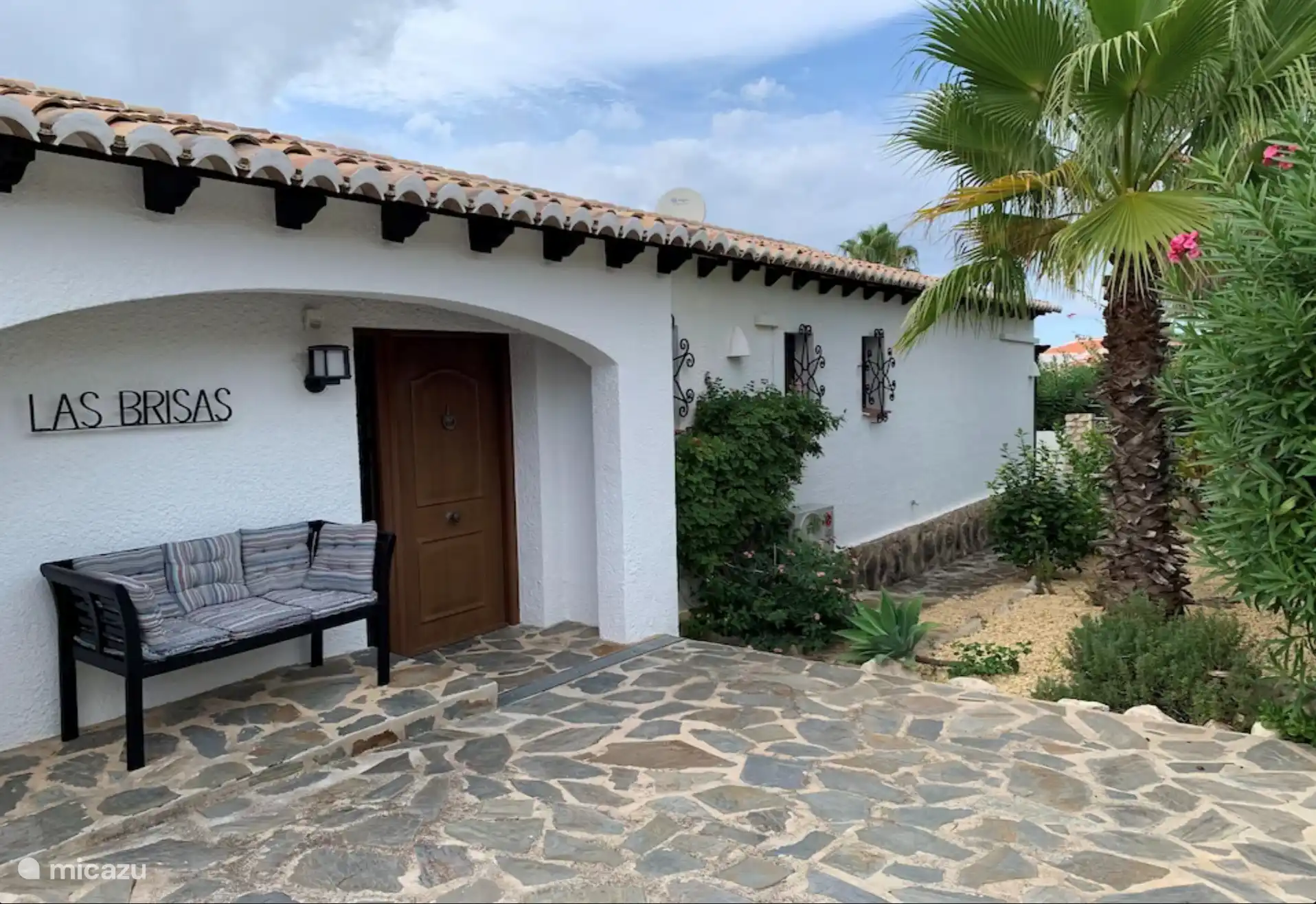 Von der Straßenseite kommen Sie durch das Schiebetor auf die vordere Terrasse mit Garten und privatem Platz für das Auto. 