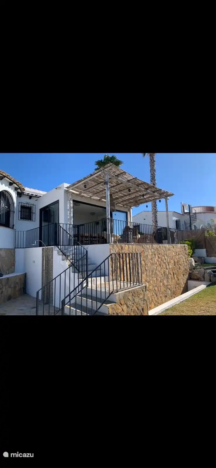 Vom Pool aus geht es die Treppe hinauf auf die obere Terrasse, durch die Innenterrasse mit Esstisch und Schiebetüren und dann in das Wohnzimmer.